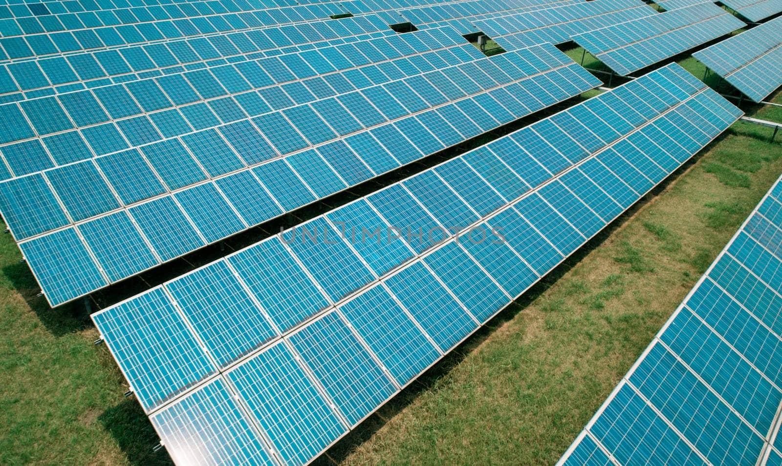 Aerial shot of solar panels farm on the green field. Renewable alternative green energy concept.