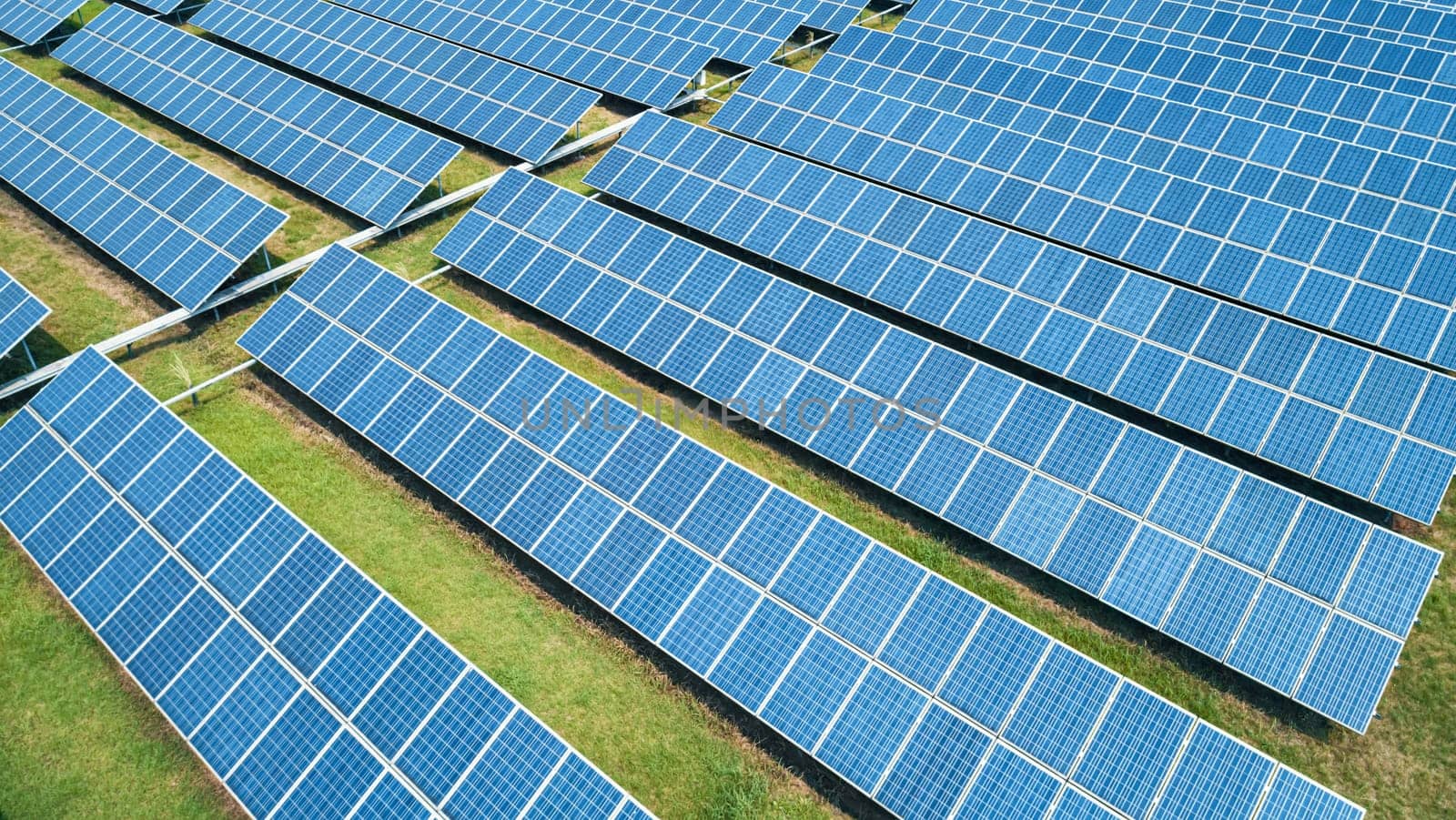 Aerial shot of solar panels farm on the green field. Renewable alternative green energy concept.