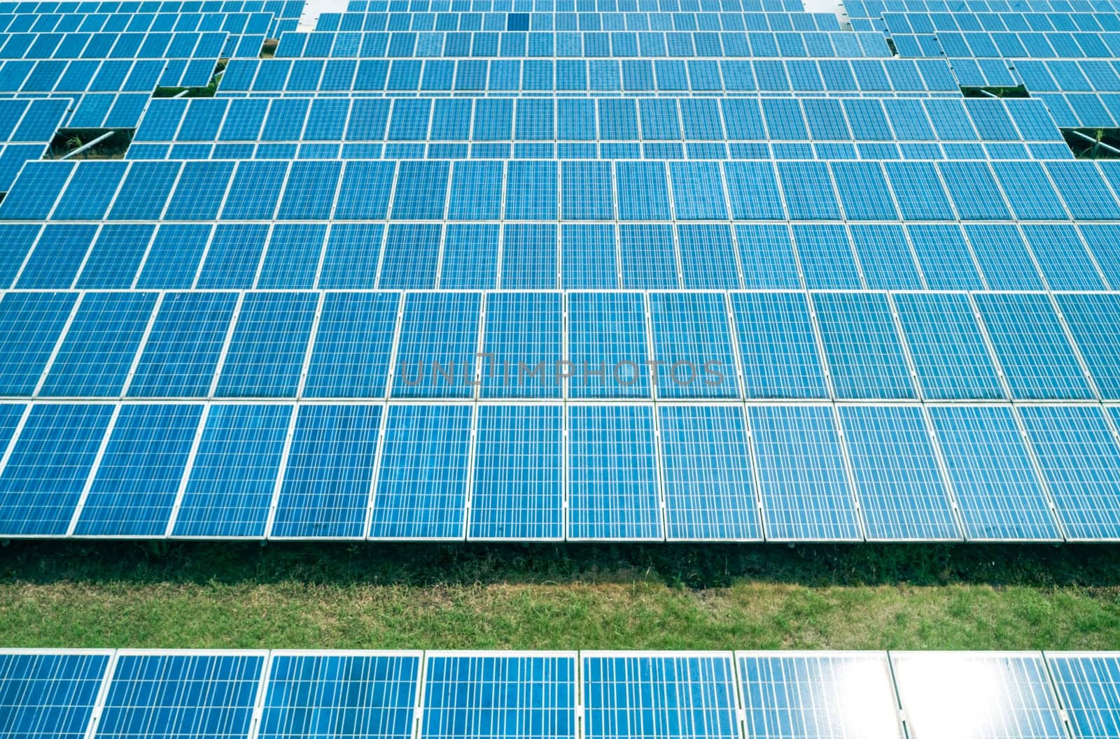 Aerial shot of solar panels farm on the green field. Renewable alternative green energy concept.