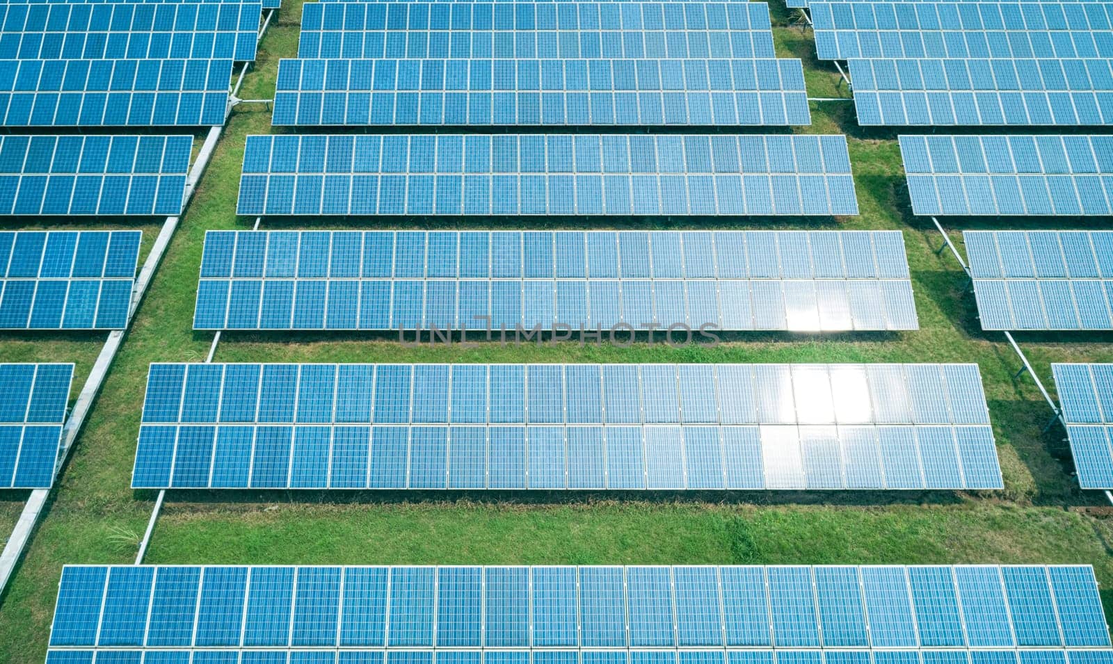 Aerial shot of solar panels farm on the green field. Renewable alternative green energy concept.