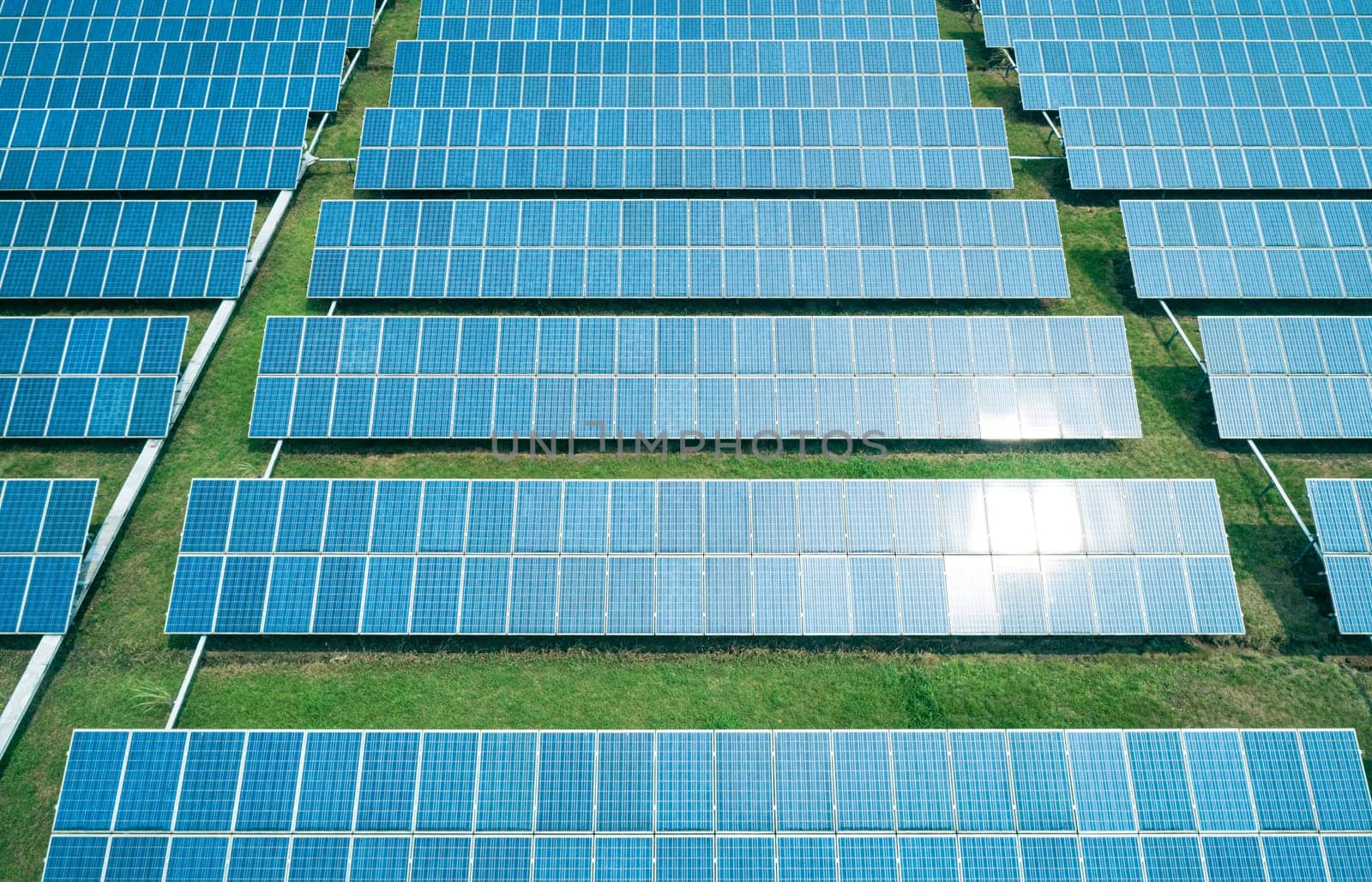 Aerial shot of solar panels farm on the green field. Renewable alternative green energy concept. by Busker