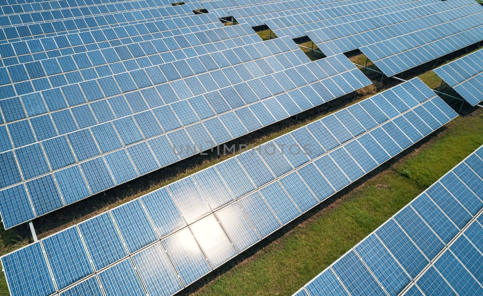 Aerial shot of solar panels farm on the green field. Renewable alternative green energy concept.