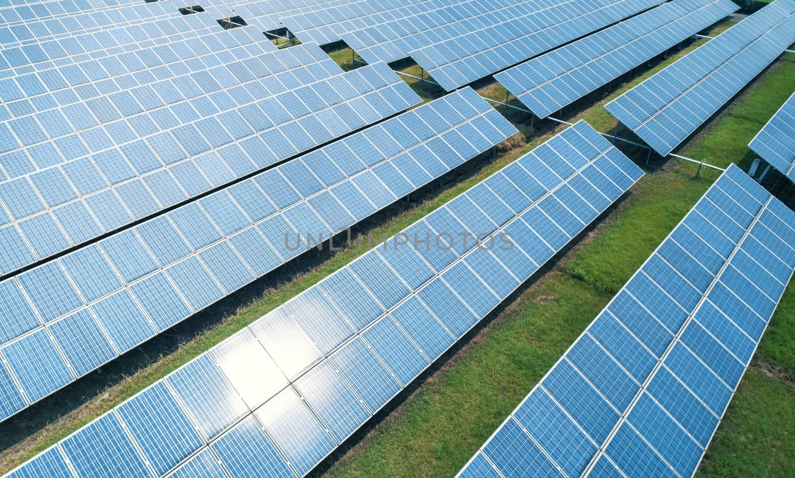 Aerial shot of solar panels farm on the green field. Renewable alternative green energy concept. by Busker