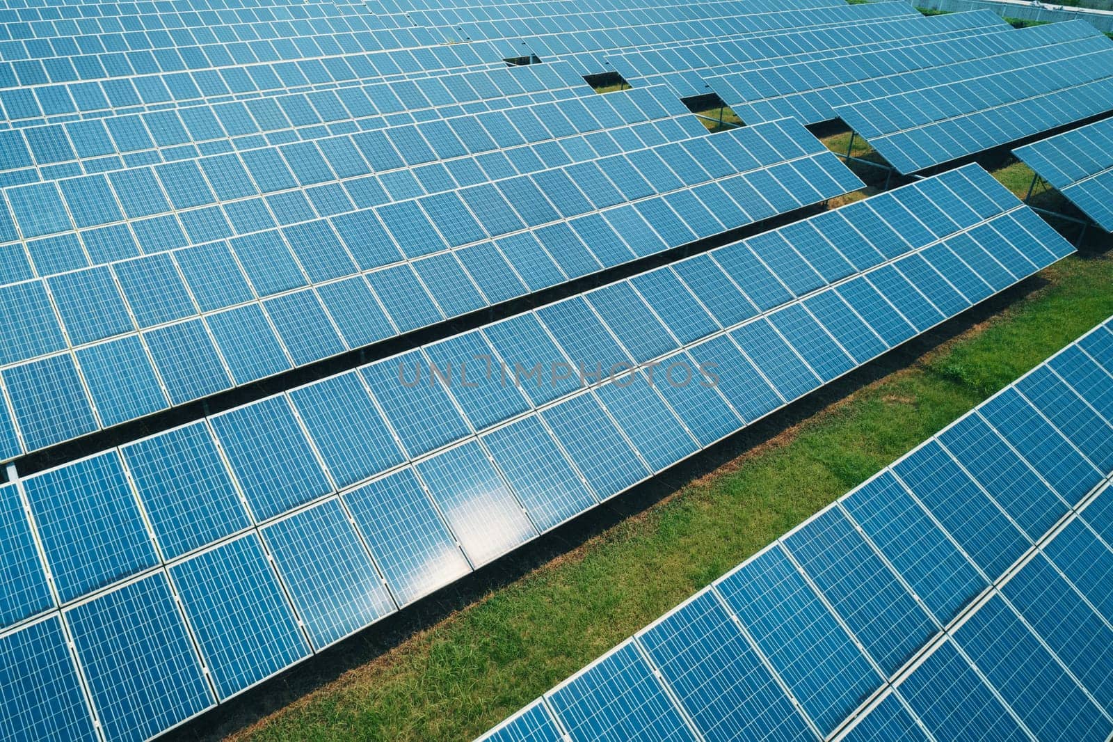 Aerial shot of solar panels farm on the green field. Renewable alternative green energy concept. by Busker