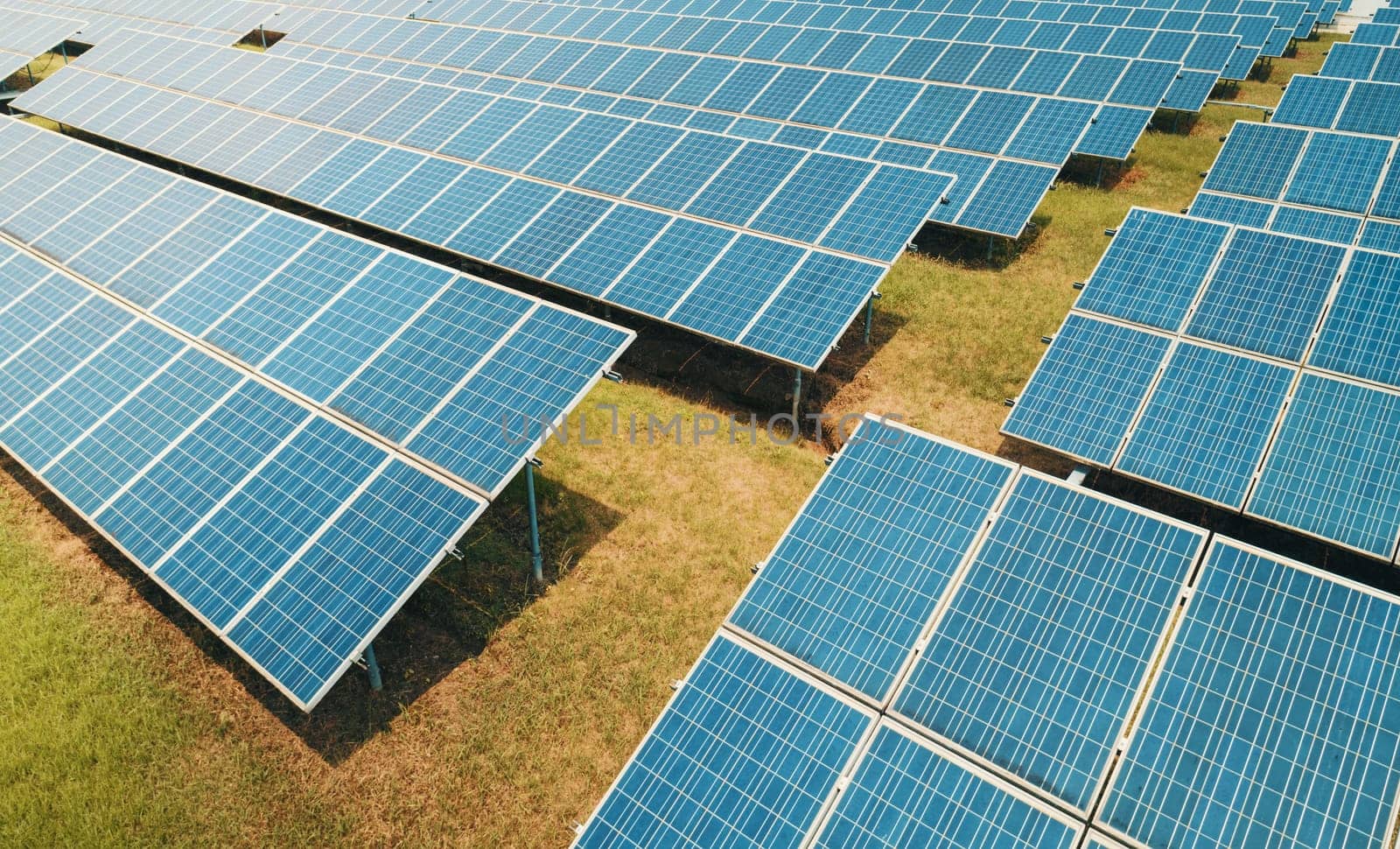 Aerial shot of solar panels farm on the green field. Renewable alternative green energy concept. by Busker