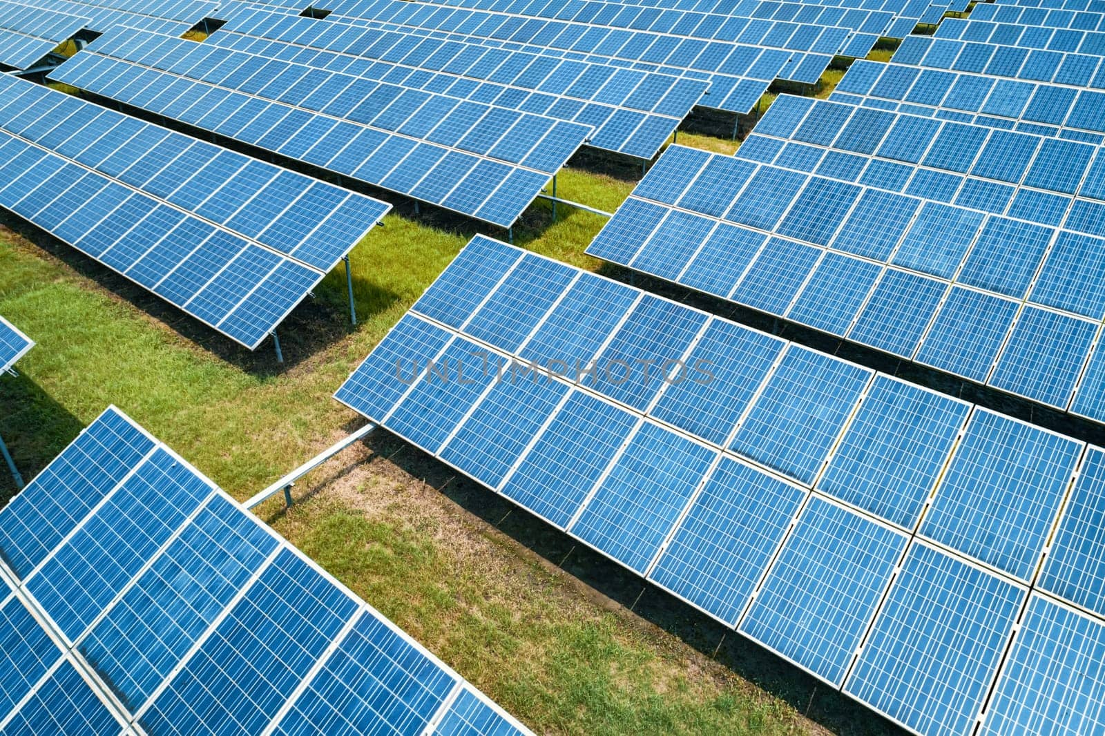 Aerial shot of solar panels farm on the green field. Renewable alternative green energy concept.