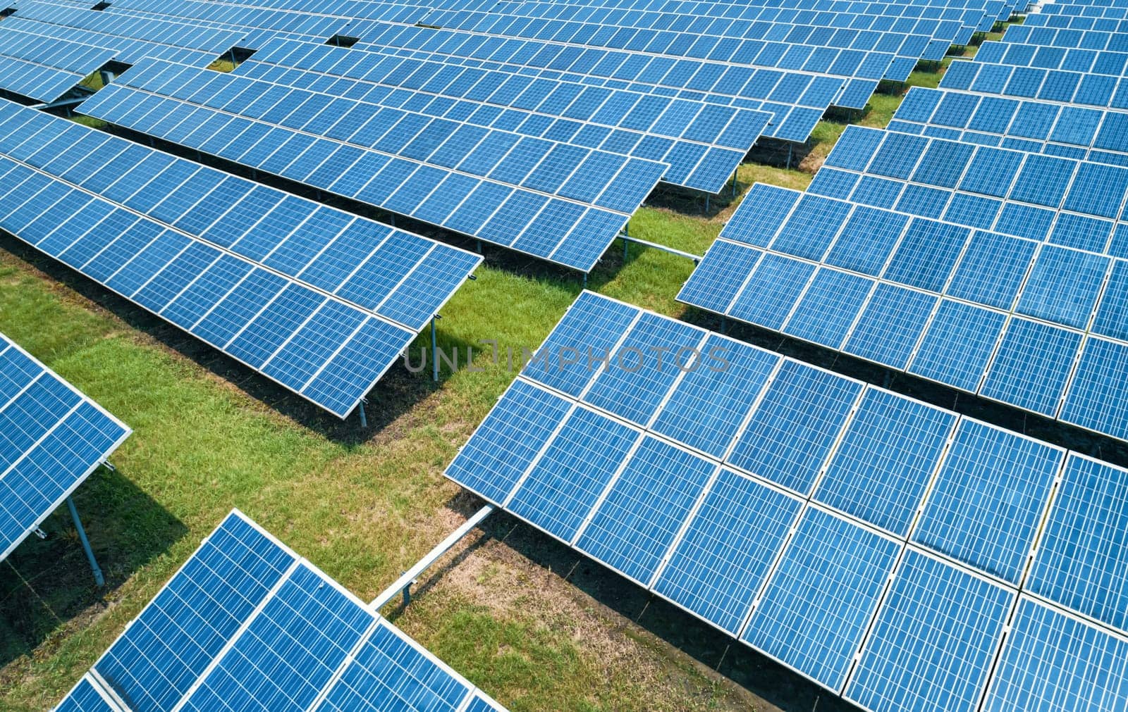 Aerial shot of solar panels farm on the green field. Renewable alternative green energy concept.