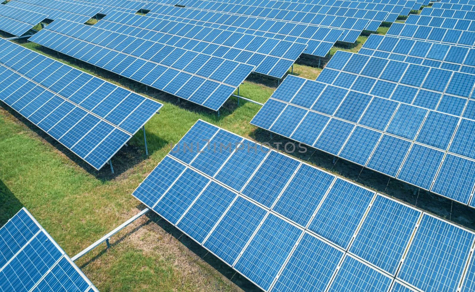 Aerial shot of solar panels farm on the green field. Renewable alternative green energy concept. by Busker