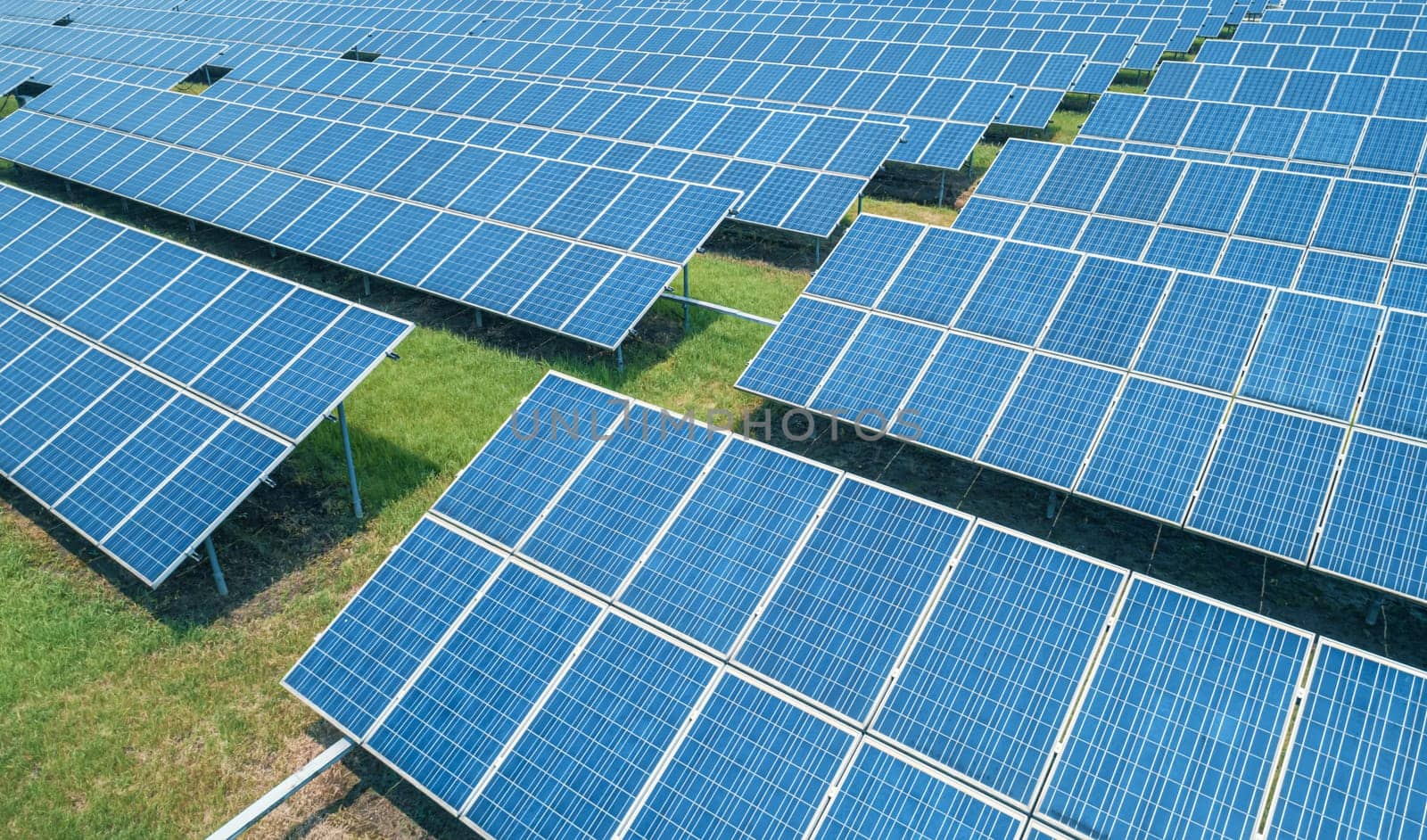 Aerial shot of solar panels farm on the green field. Renewable alternative green energy concept.