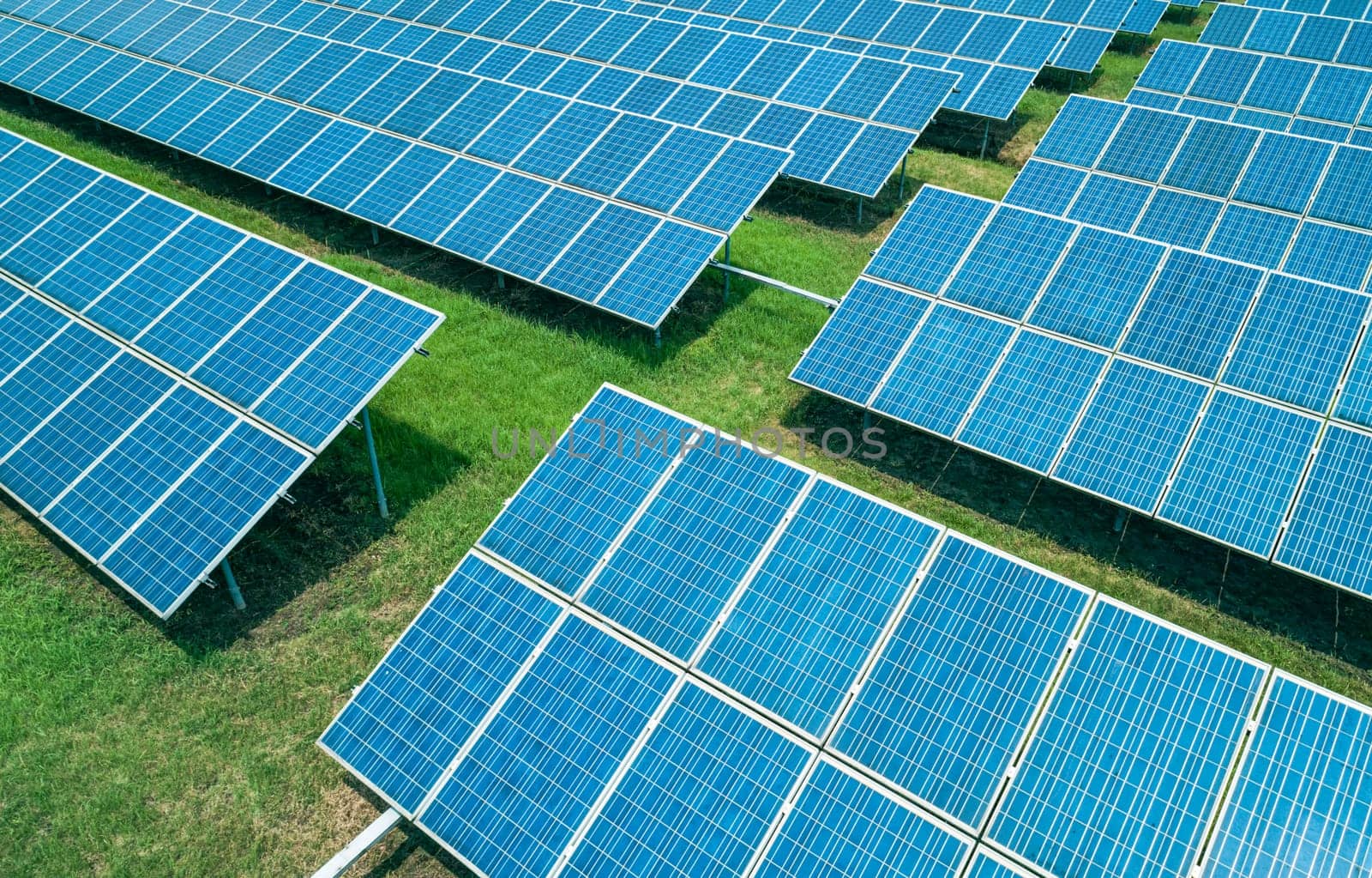 Aerial shot of solar panels farm on the green field. Renewable alternative green energy concept.