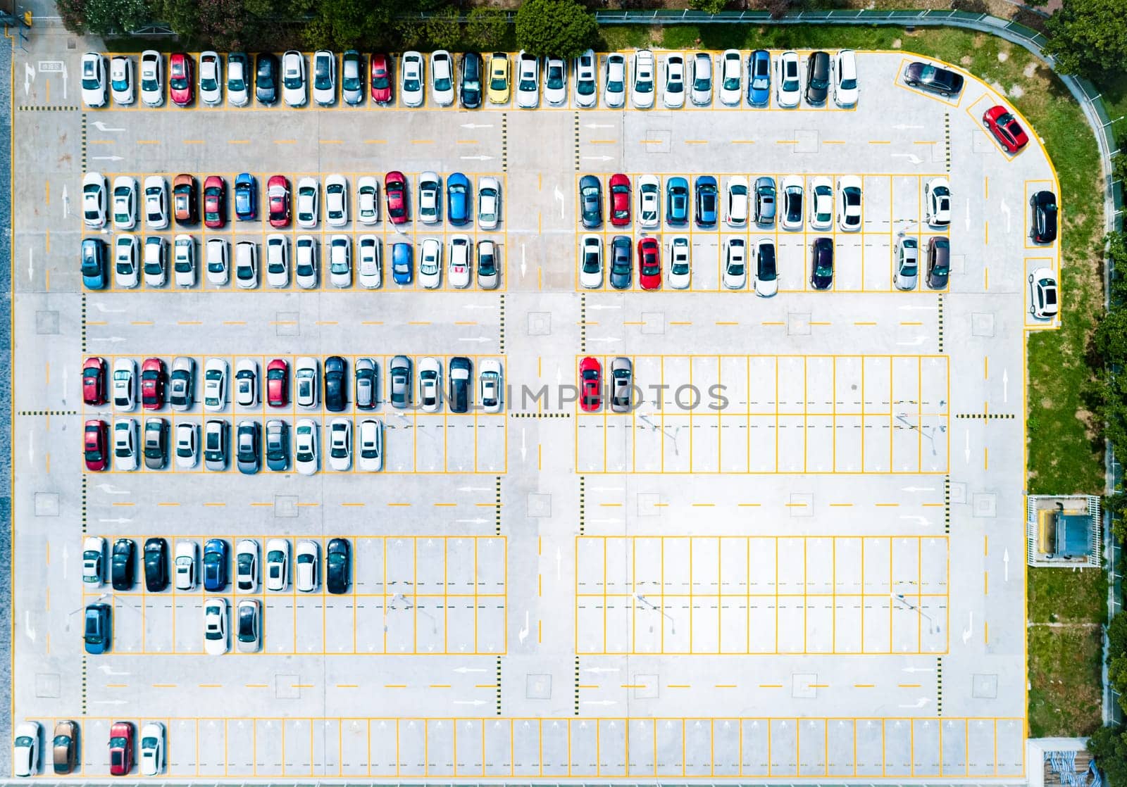 Aerial top down view a parking lot with cars of different colors.