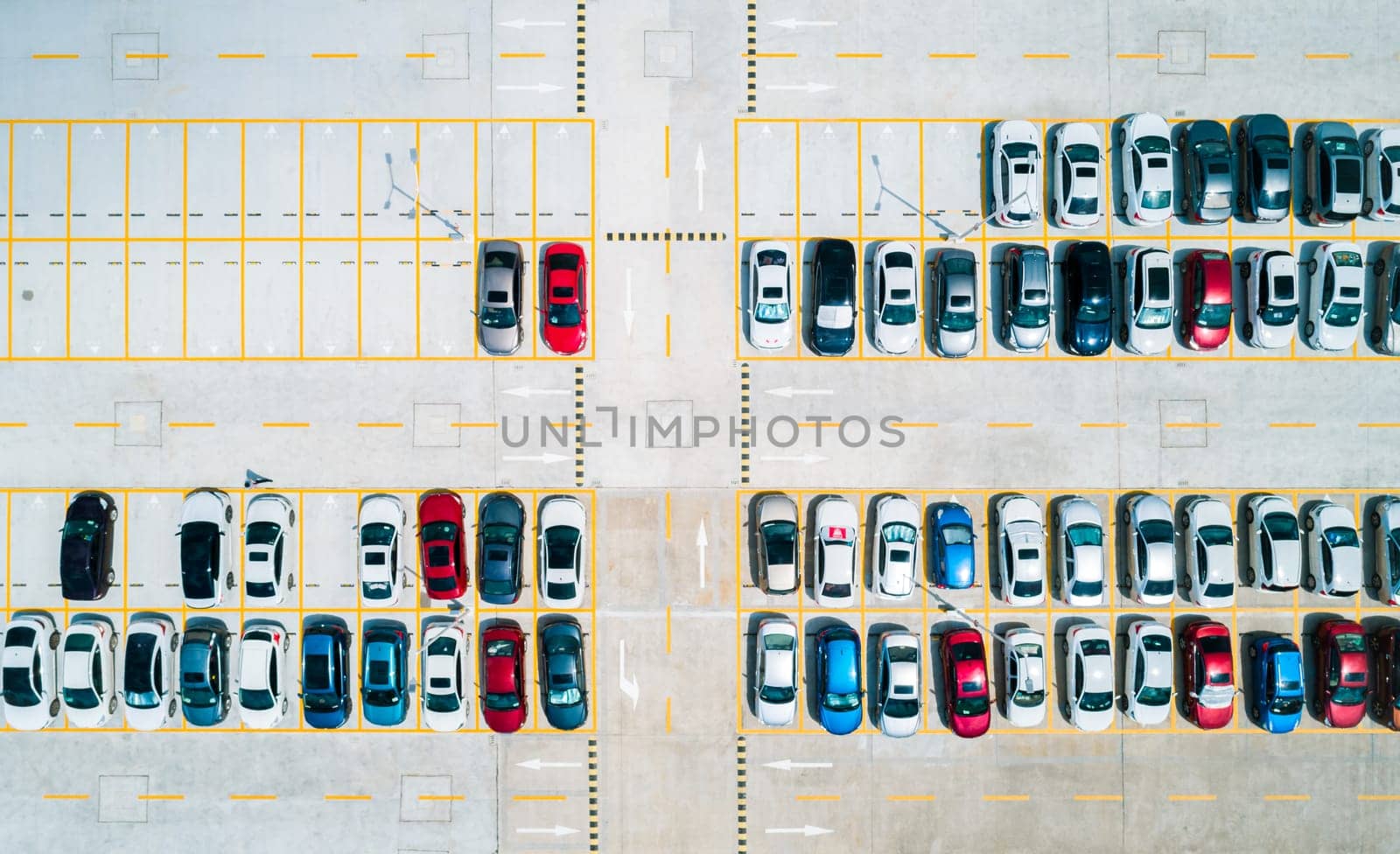 Aerial top down view a parking lot with cars of different colors.