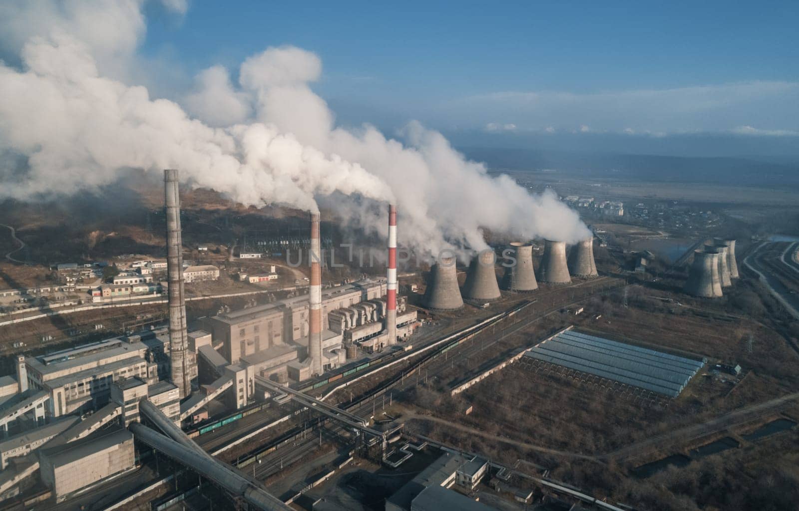 Aerial view of tall chimney pipes with grey smoke from coal power plant. Production of electricity with fossil fuel. Ecology and pollution of nature. by Busker