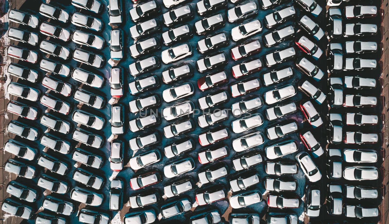 Aerial top down view of new cars parked in car parking lot. Car dealer parking lot full of new automobiles. New cars lined up for import and export business.