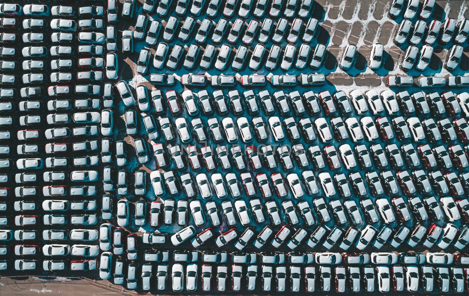 Aerial top down view of new cars parked in car parking lot. Car dealer parking lot full of new automobiles. New cars lined up for import and export business.