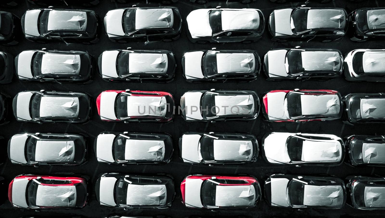 Aerial top down view of new cars parked in car parking lot. Car dealer parking lot full of new automobiles. New cars lined up for import and export business.