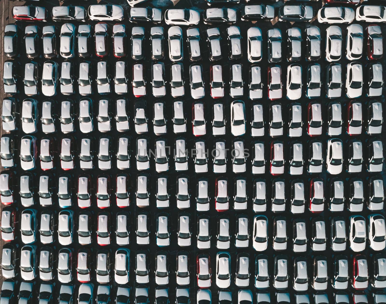 Aerial top down view of new cars parked in car parking lot. Car dealer parking lot full of new automobiles. New cars lined up for import and export business. by Busker