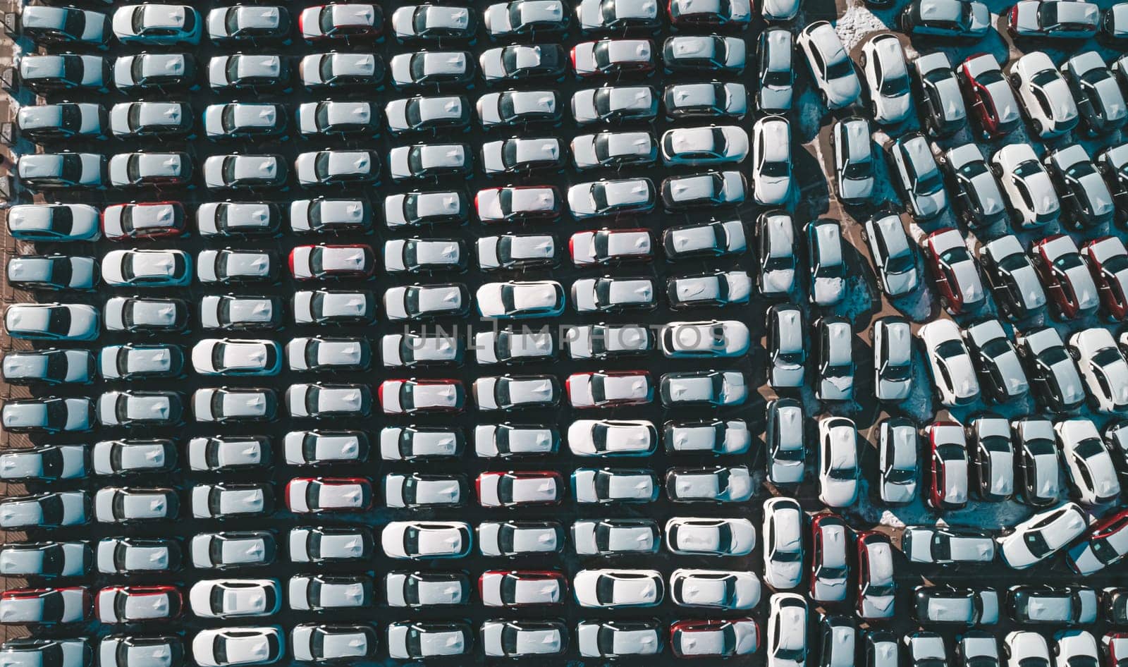 Aerial top down view of new cars parked in car parking lot. Car dealer parking lot full of new automobiles. New cars lined up for import and export business.