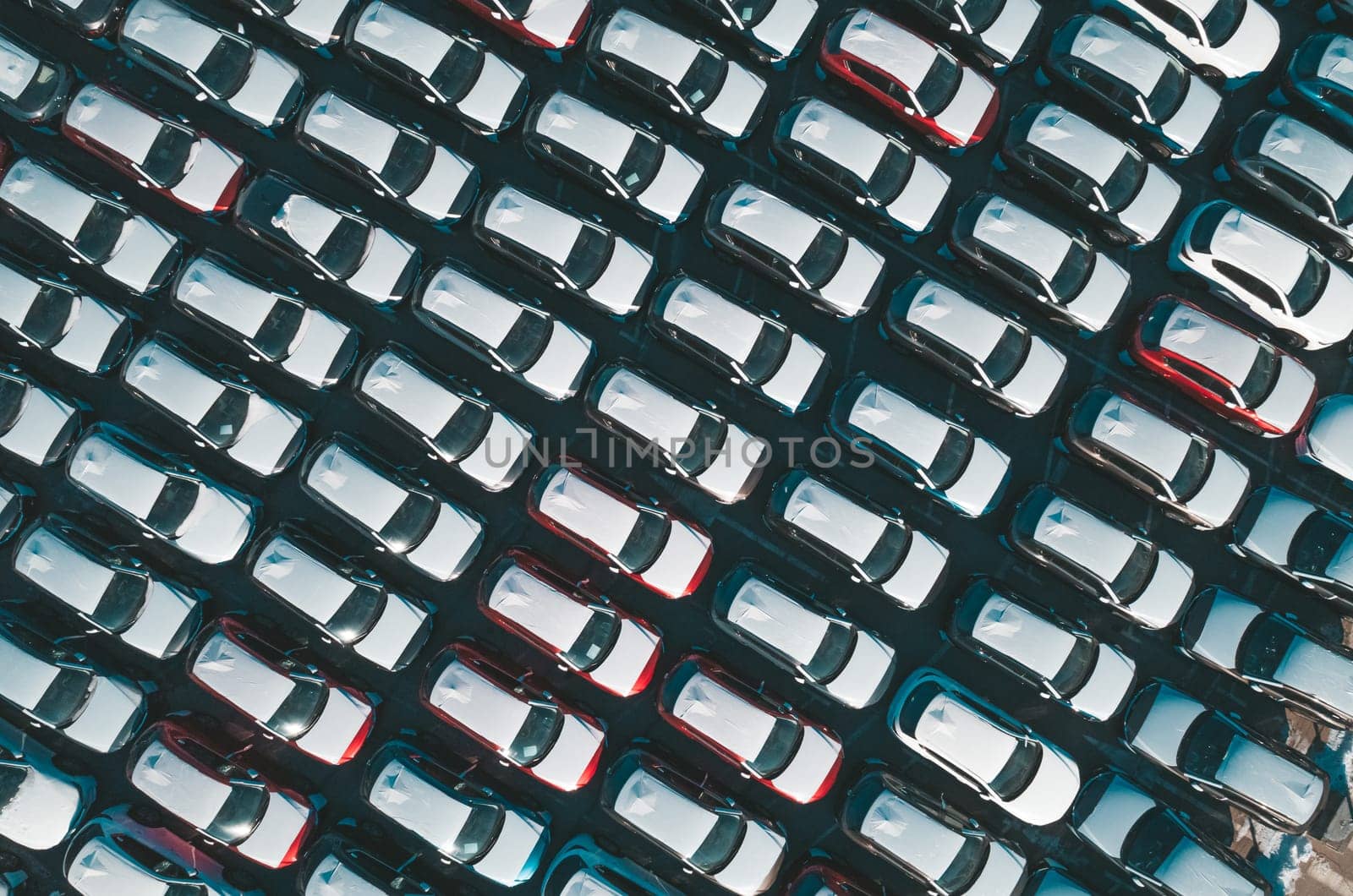 Aerial top down view of new cars parked in car parking lot. Car dealer parking lot full of new automobiles. New cars lined up for import and export business. by Busker