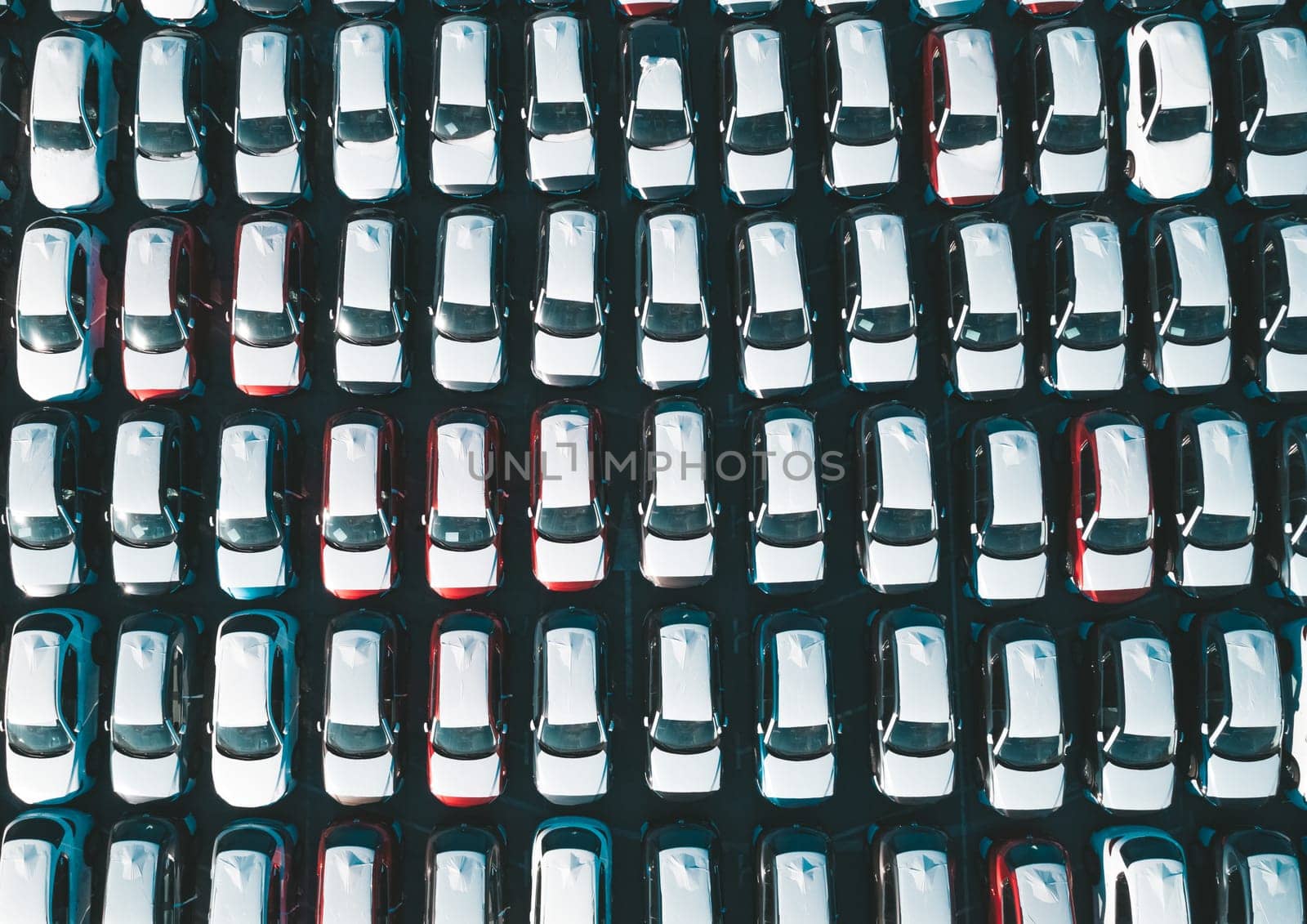 Aerial top down view of new cars parked in car parking lot. Car dealer parking lot full of new automobiles. New cars lined up for import and export business. by Busker