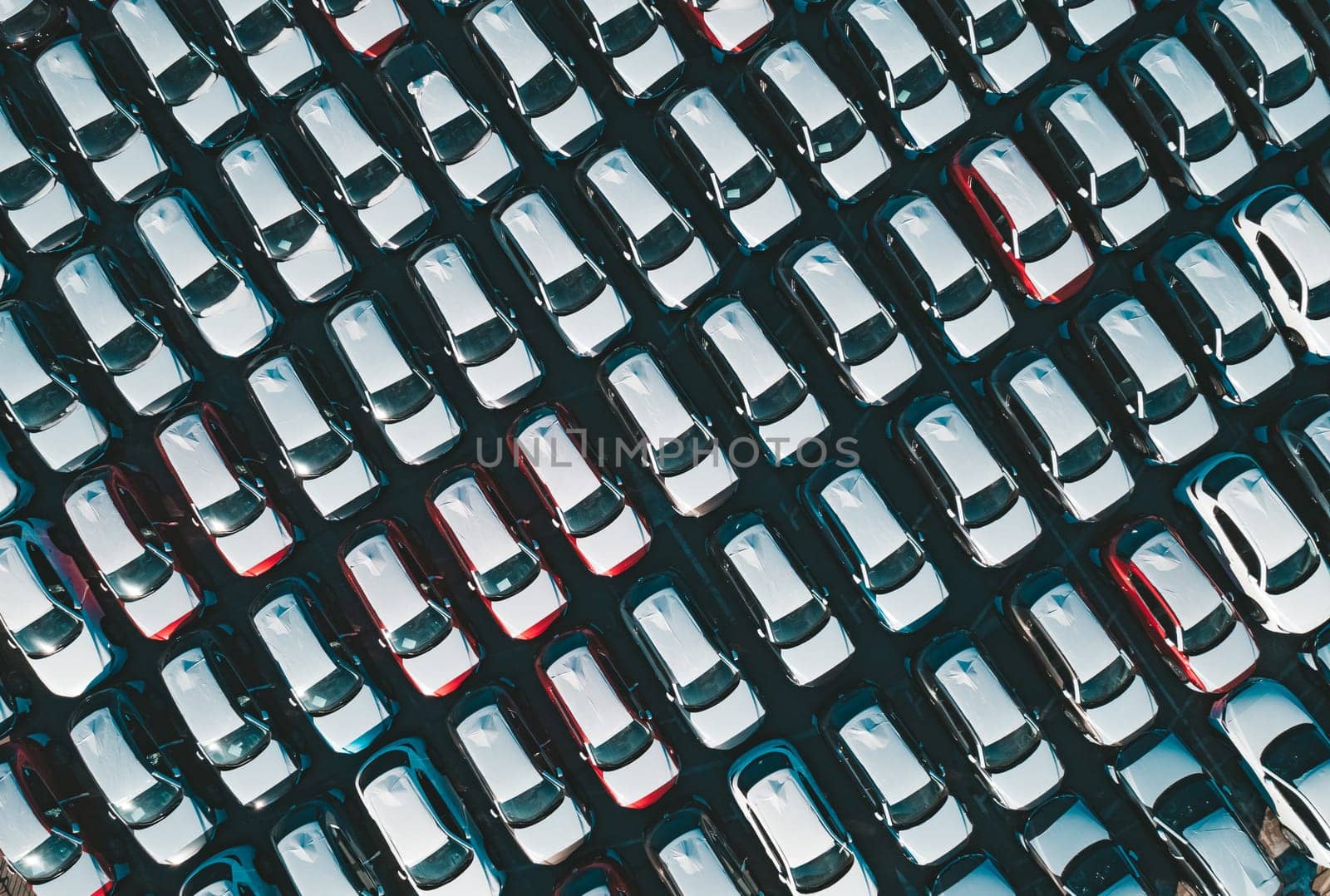 Aerial top down view of new cars parked in car parking lot. Car dealer parking lot full of new automobiles. New cars lined up for import and export business. by Busker