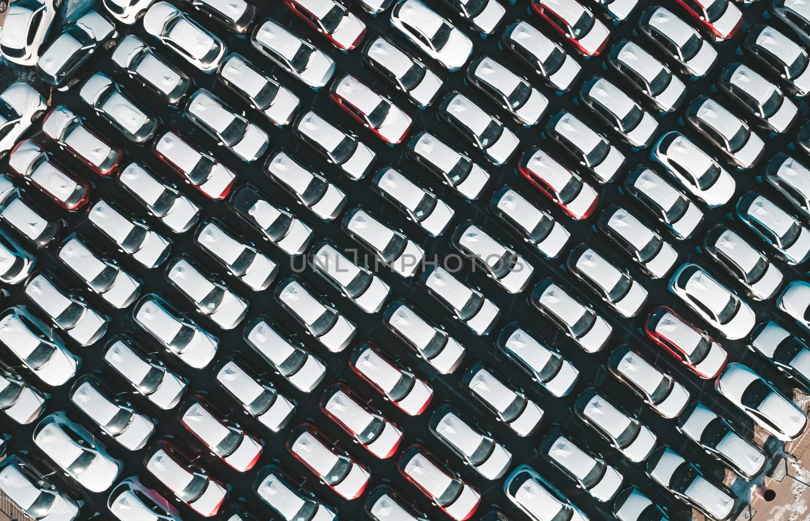 Aerial top down view of new cars parked in car parking lot. Car dealer parking lot full of new automobiles. New cars lined up for import and export business. by Busker