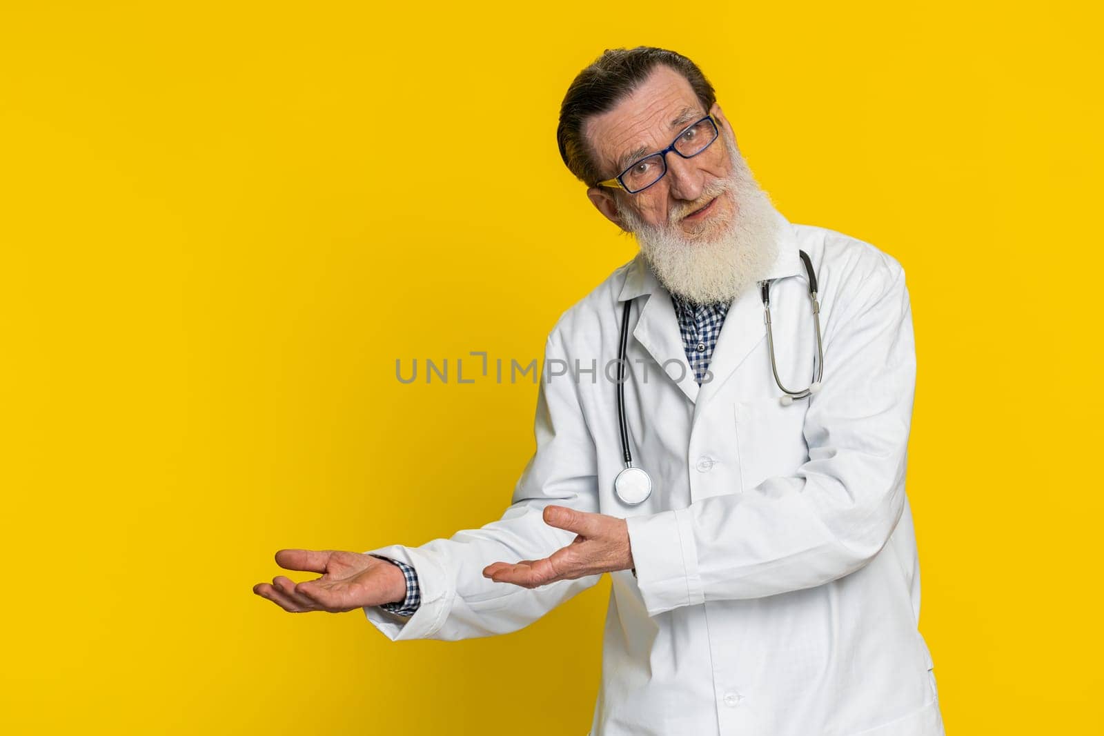 Senior elderly doctor cardiologist man raising hands asking what why reason of failure demonstrating disbelief irritation by troubles. Apothecary pharmacy old grandfather isolated on yellow background