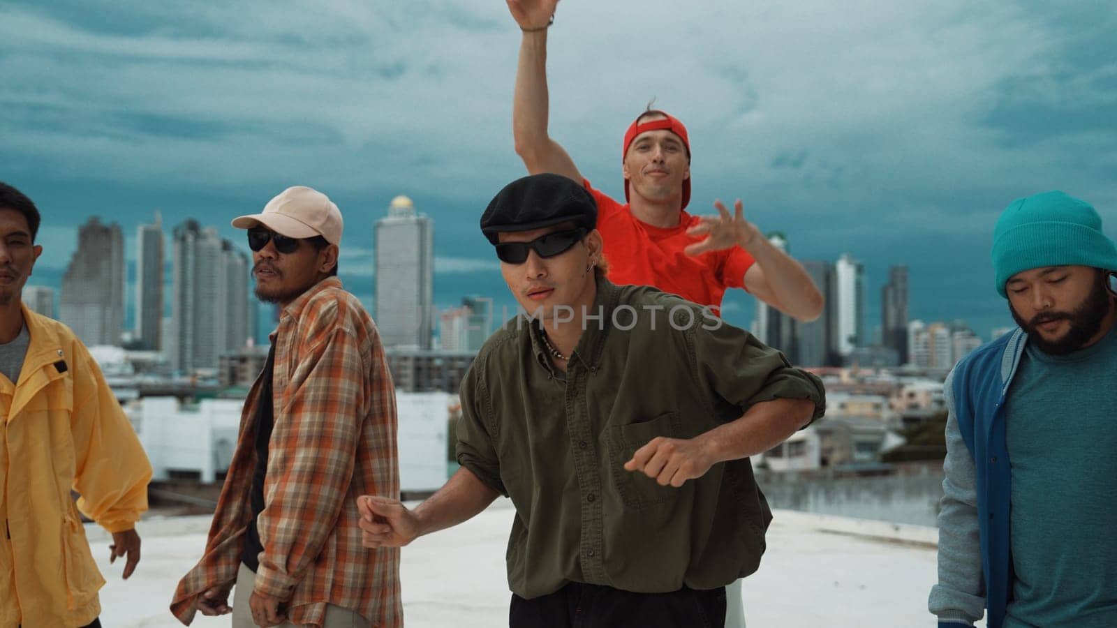 Skilled multicultural street dancing group pose at camera at roof top while moving to the rhyme and music. Young people or teenager moving to funky music, break dance. Outdoor sport 2024. Endeavor.