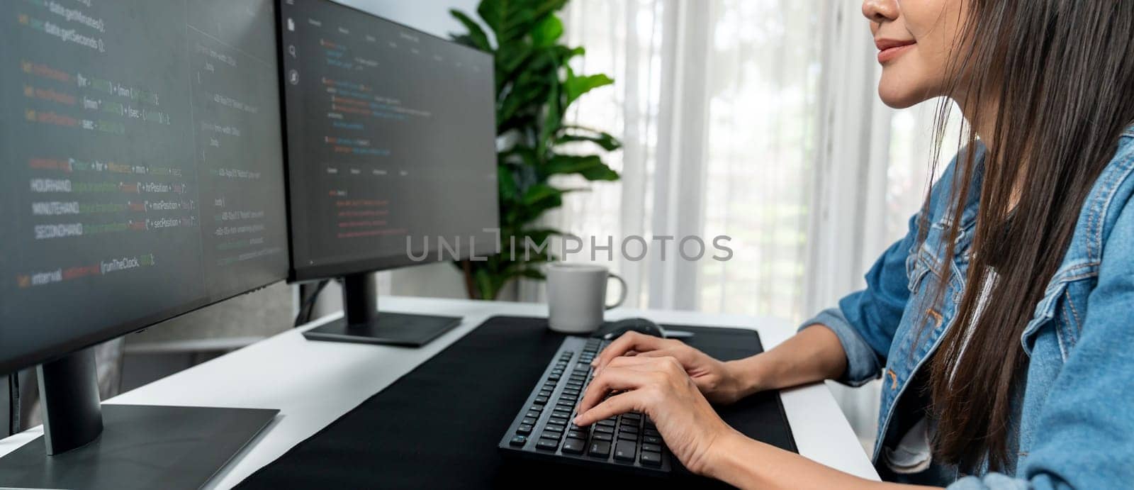 Young Asian in IT developer creating with typing online information on pc with coding program data of website application, wearing jeans shirt. surrounded by safety analysis two screens. Stratagem.