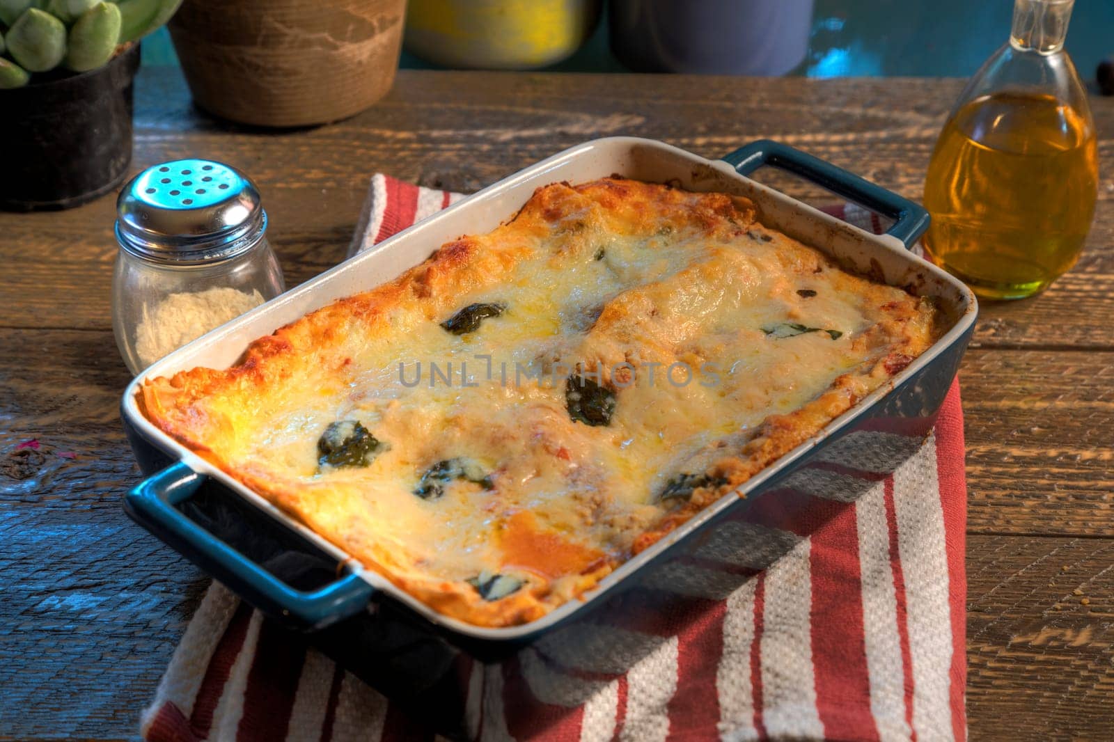 Side view of lasagna in ceramic baking dish on natural wood surface