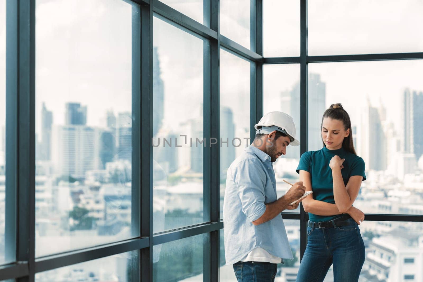 Professional smart architect engineer team discuss and solve building construction problems. Engineer taking a note while listening manager sharing idea about work surrounded by skyscraper. Tracery.