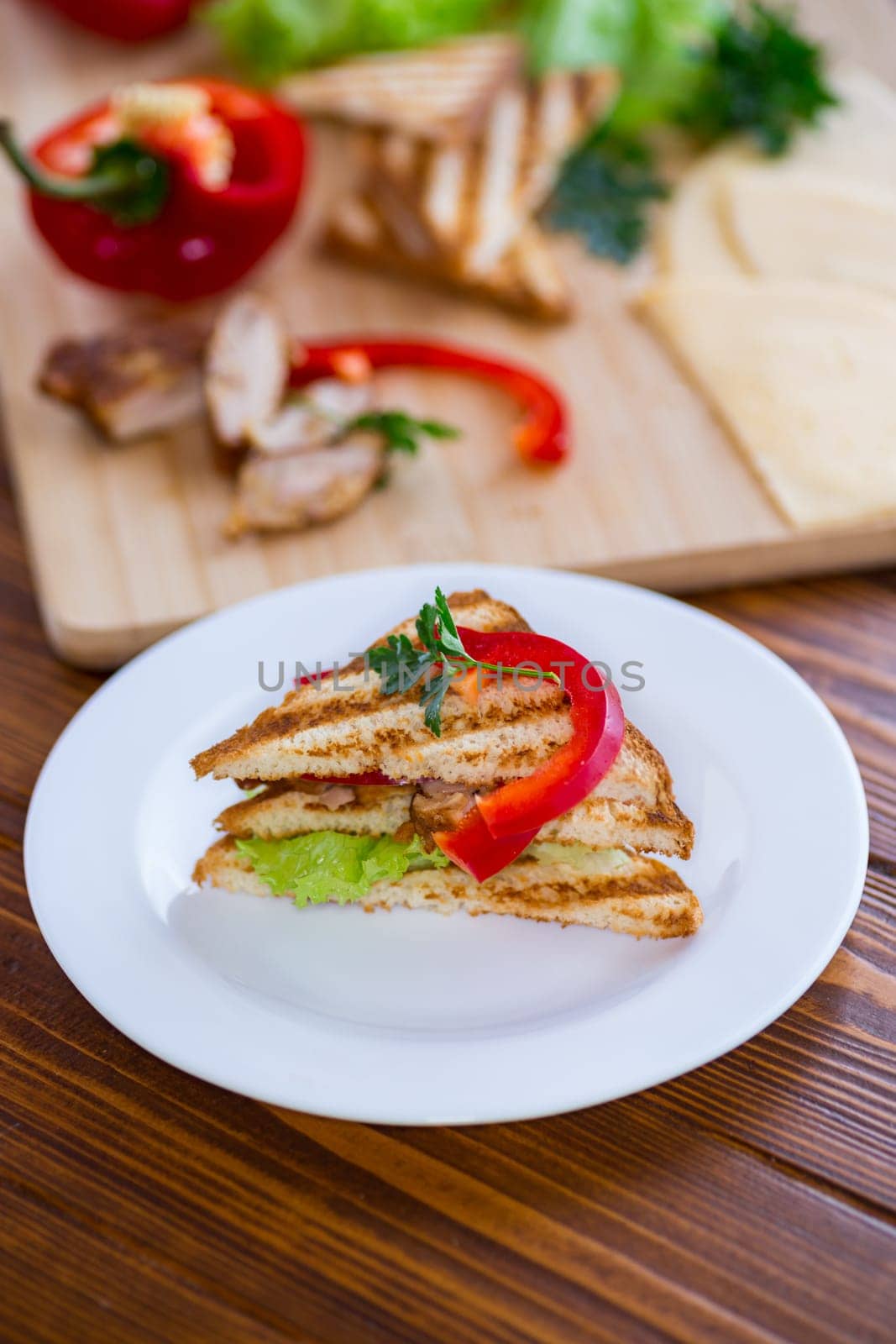 fried toast with chicken, salad, greens on a wooden table .