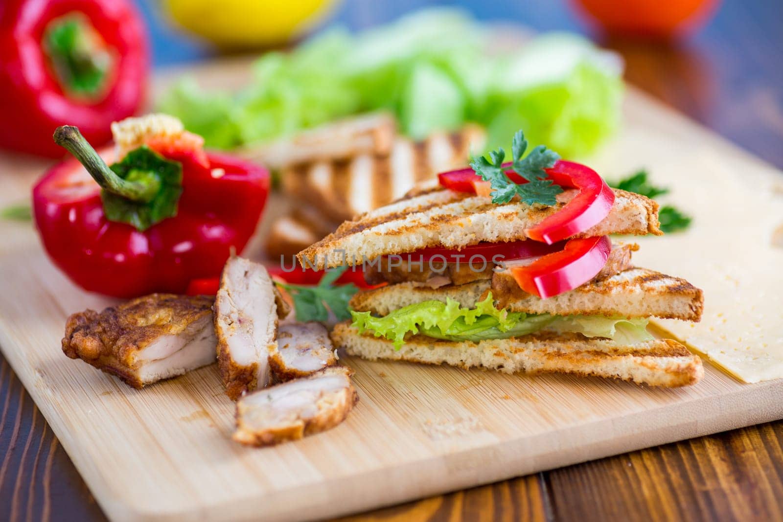 fried toast with chicken, salad, greens on a wooden table .