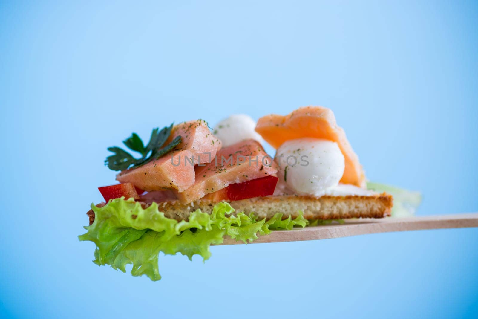fried toast with salmon, cream cheese, salad, isolated on blue background .