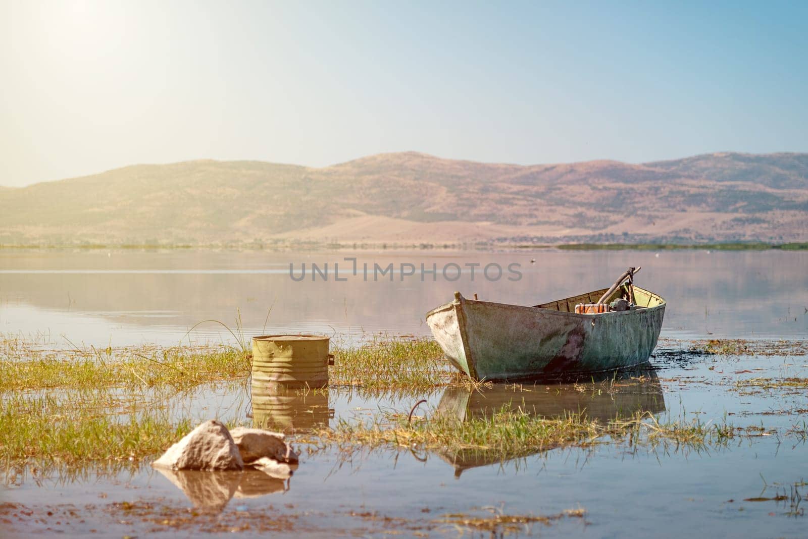 Abandoned old fishing boat in the lake that started to dry up and recede due to global warming. by Sonat