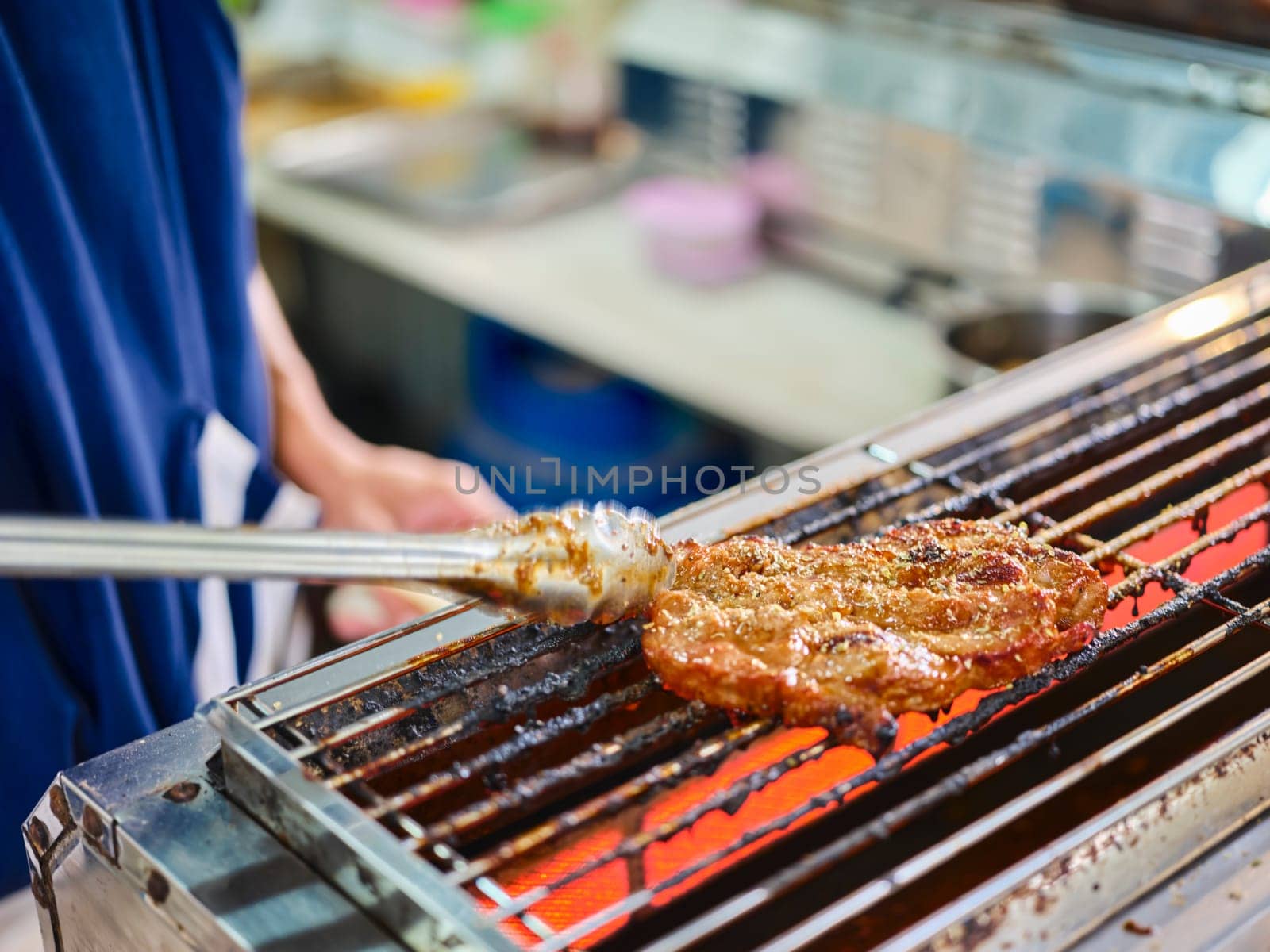 Man use meat tongs grills multiple sliced meat . by Hepjam