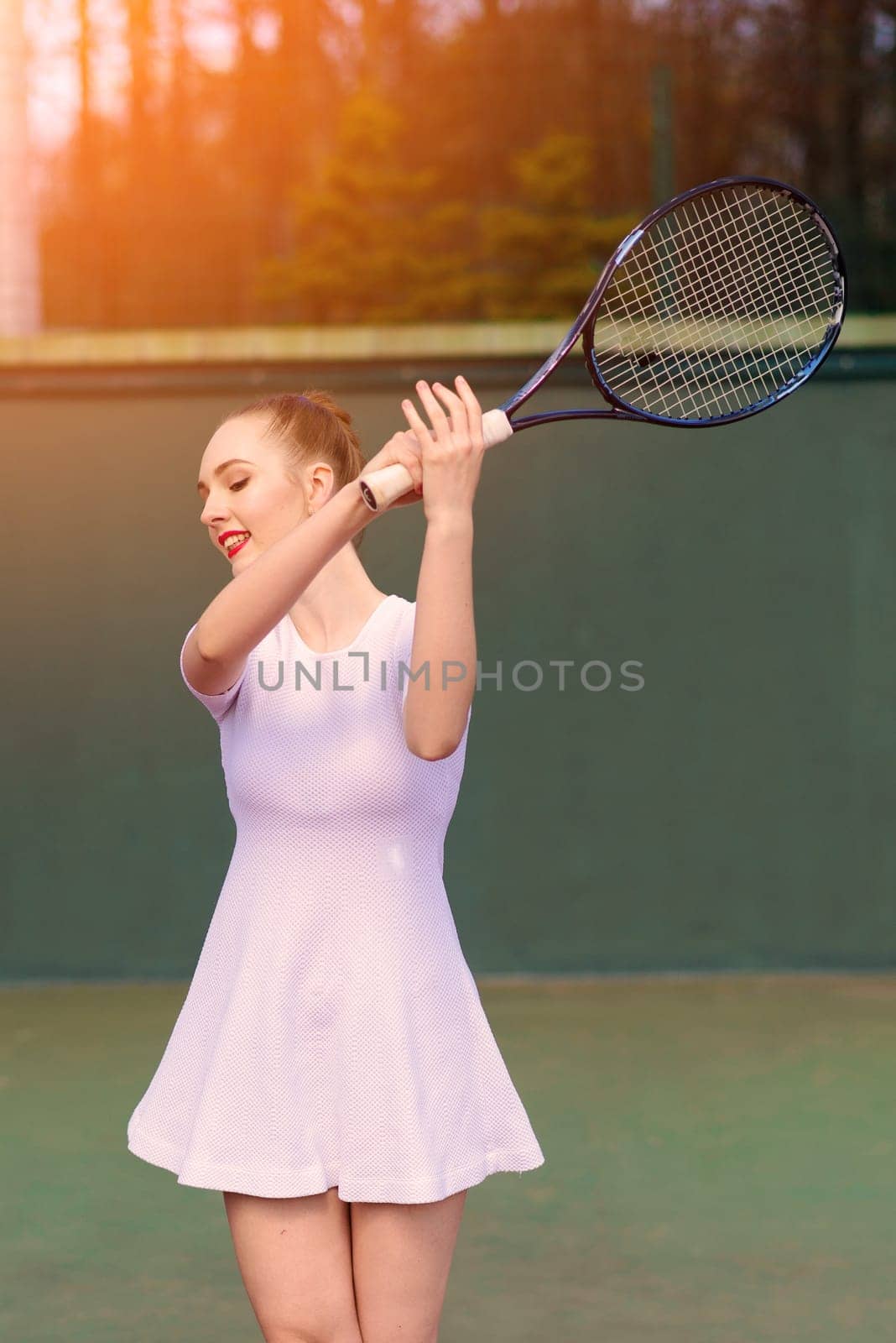 Sexy girl tennis player in white dress and heels holding tennis racket on the court. Young woman is playing tennis, sport