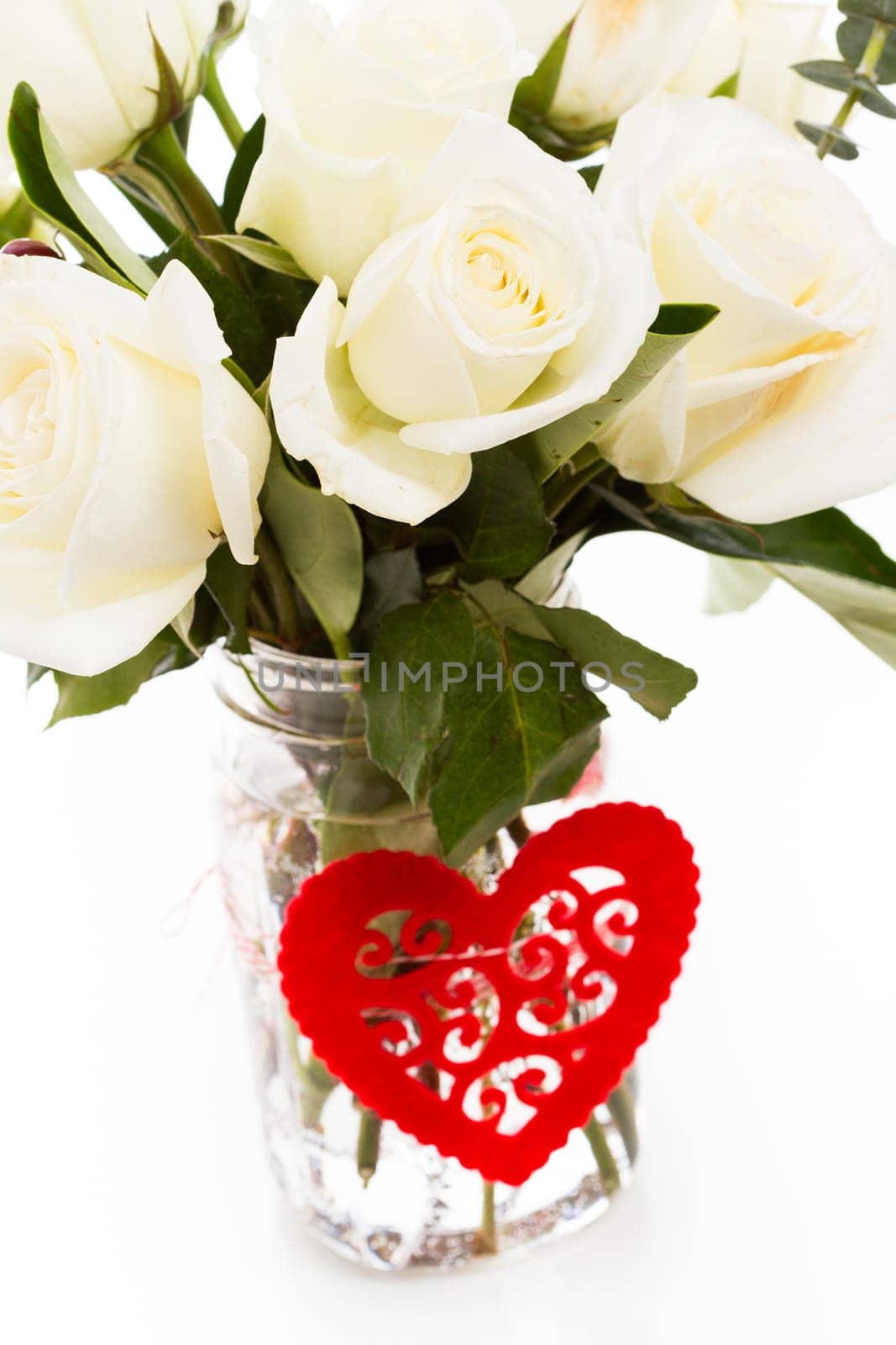 Bouquet of white roses in vase with red heart.