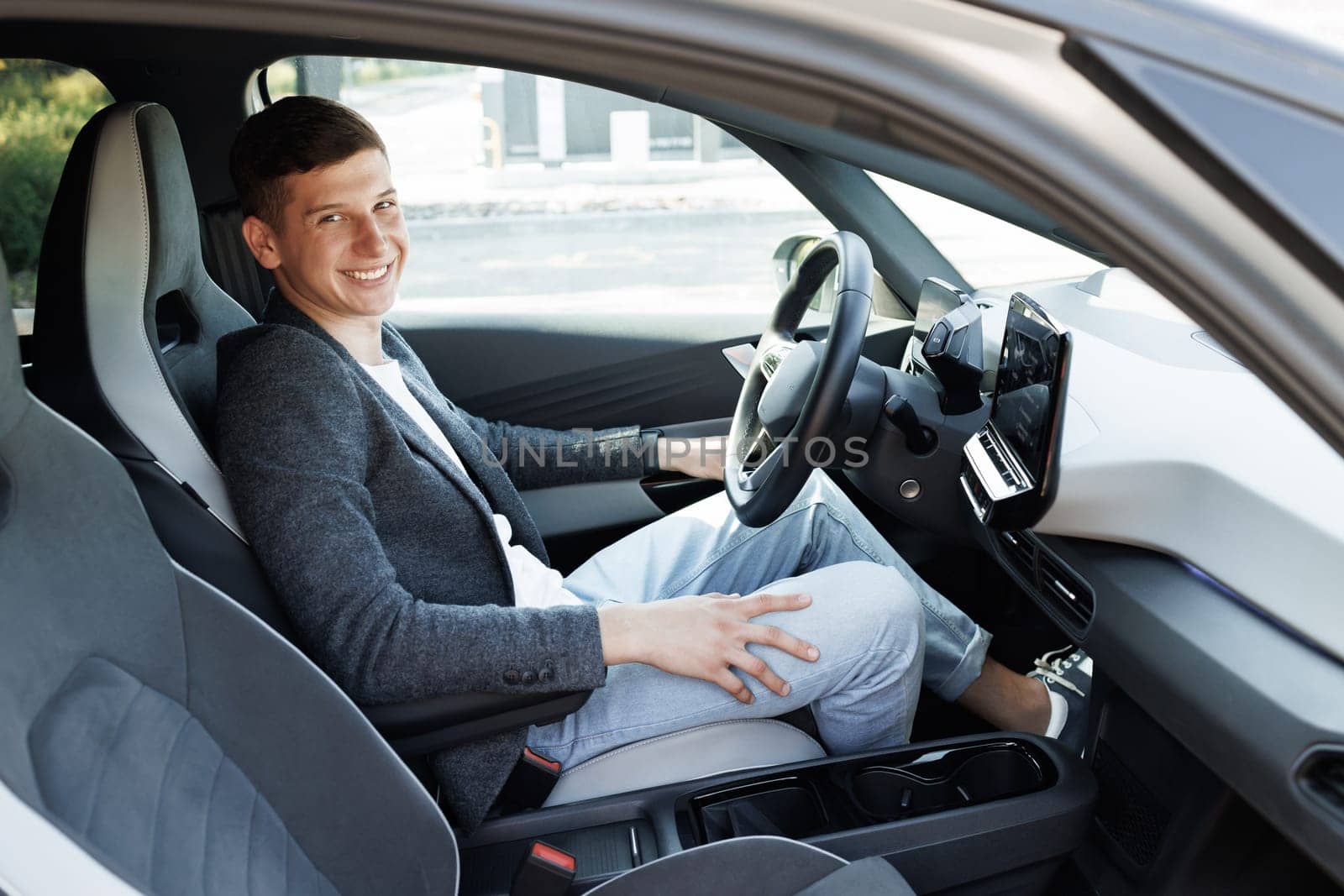 Portrait of an attractive man smiling before starting to work as a taxi driver of a car sharing service on a mobile app. Joyful man driving car, going on trip during summer vacation by uflypro