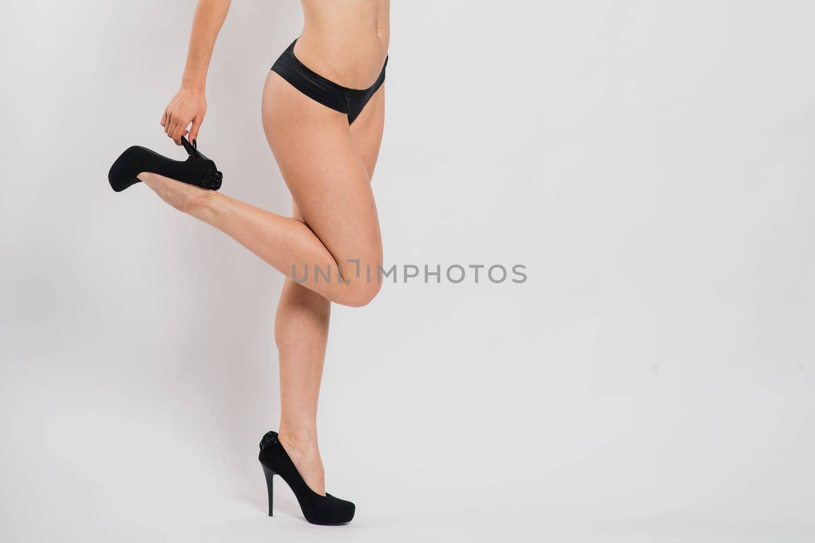 Cute brunette female model posing, wearing black and red underwear in a white studio