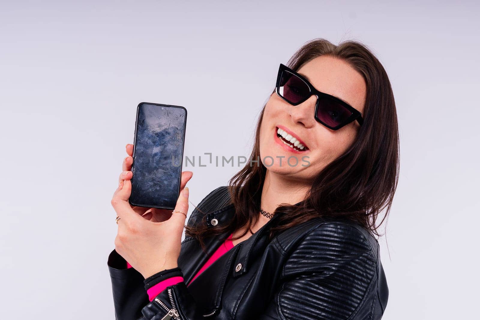 A frustrated young woman with broken phone in her hands. White isolated background. Broken Gadget