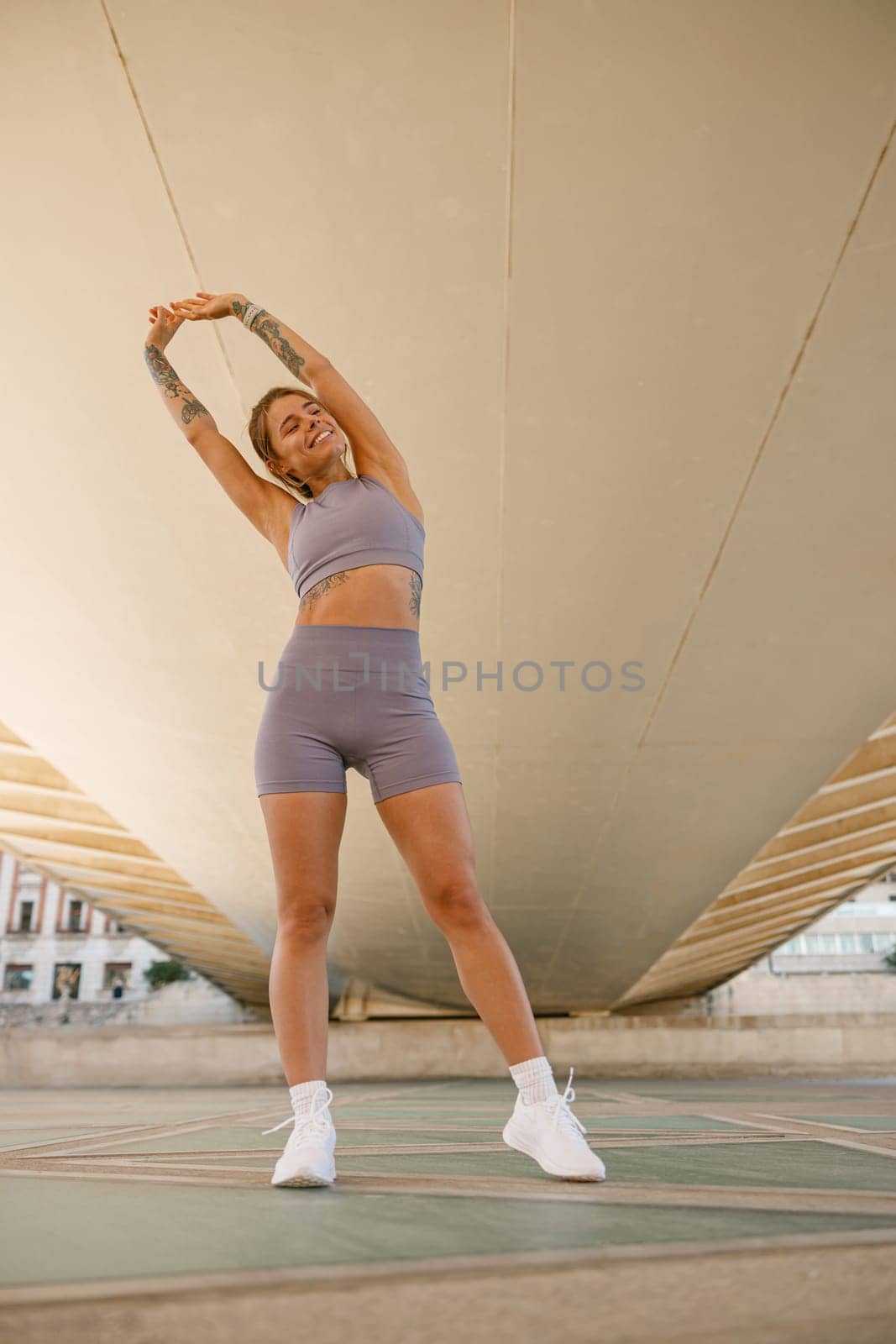 Young sportswoman in tracksuit is stretching outdoor and preparing to jogging. Healthy life concept