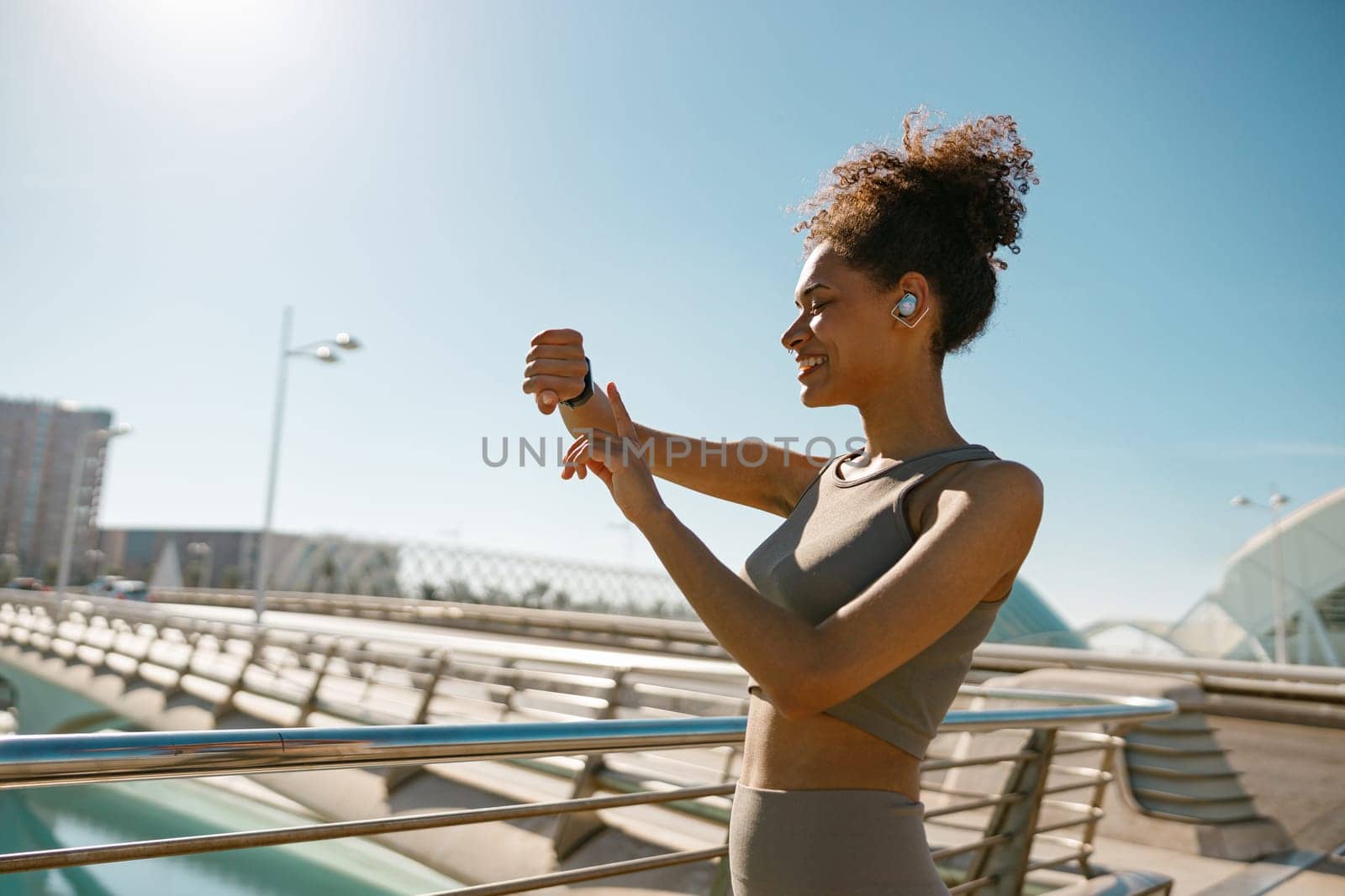 Young woman in sportswear looking on smartwatch before exercising. Outdoor sports in the morning