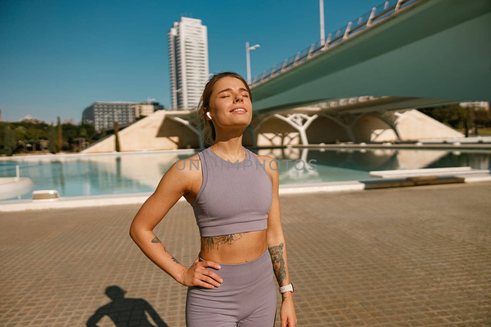 Smiling woman in sportswear have a rest after workout outside standing on bridge background