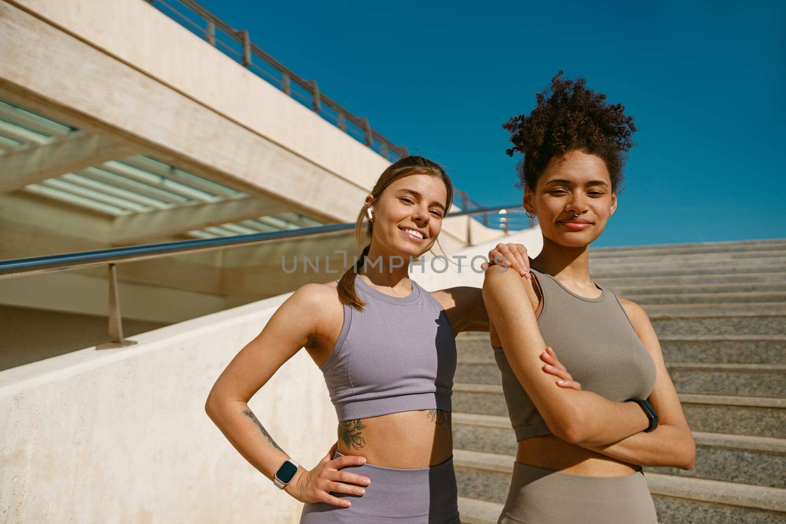 Two young female sportswomen have a rest after morning jogging outdoors and looks camera by Yaroslav_astakhov