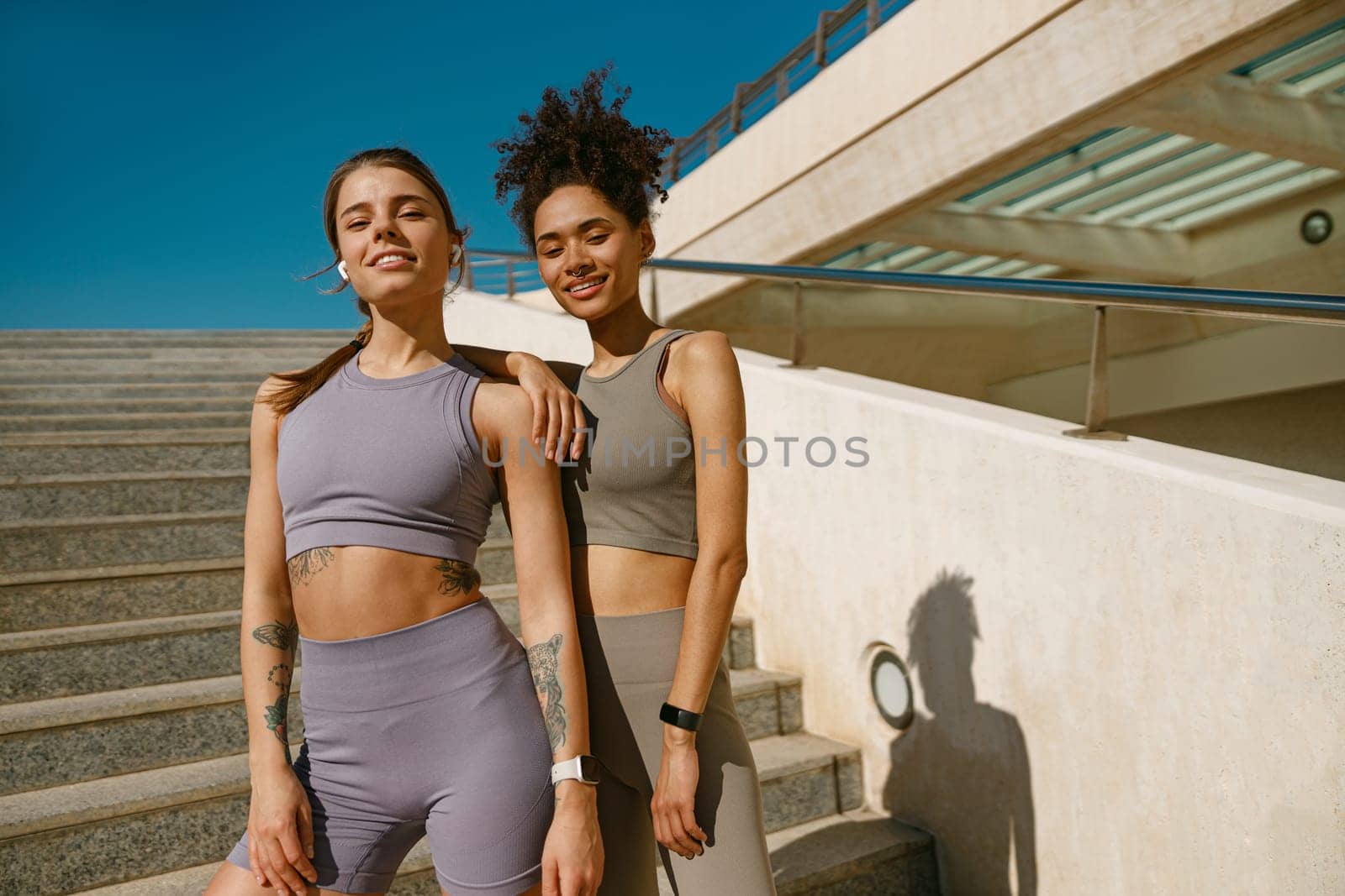 Two young female sportswomen have a rest after morning jogging outdoors and looks camera by Yaroslav_astakhov