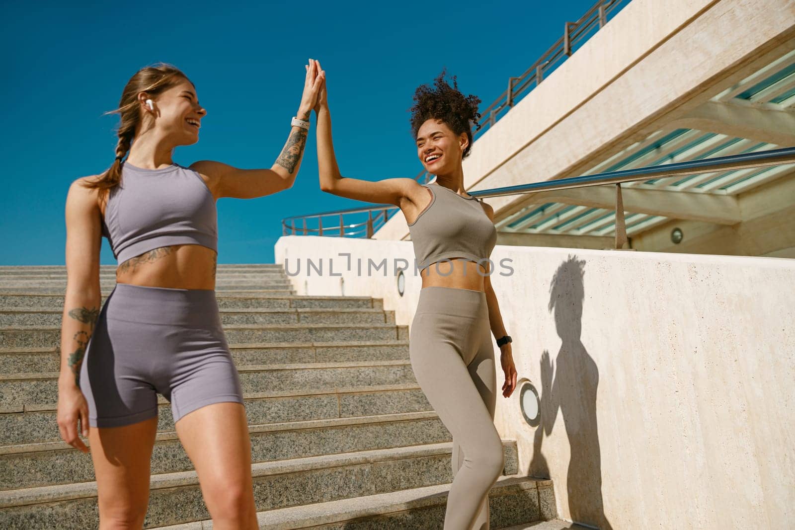 Happy female friends doing gesture of sport shake hand after exercising outside by Yaroslav_astakhov