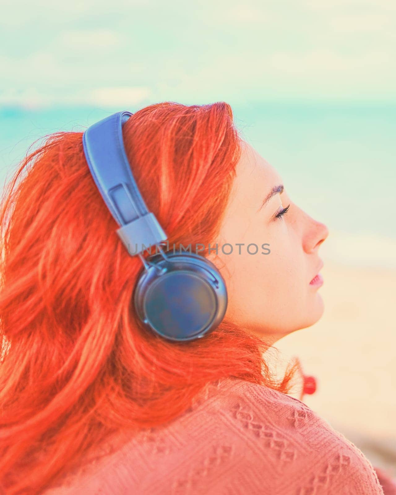Beautiful woman listening to music on the beach. by savconstantine
