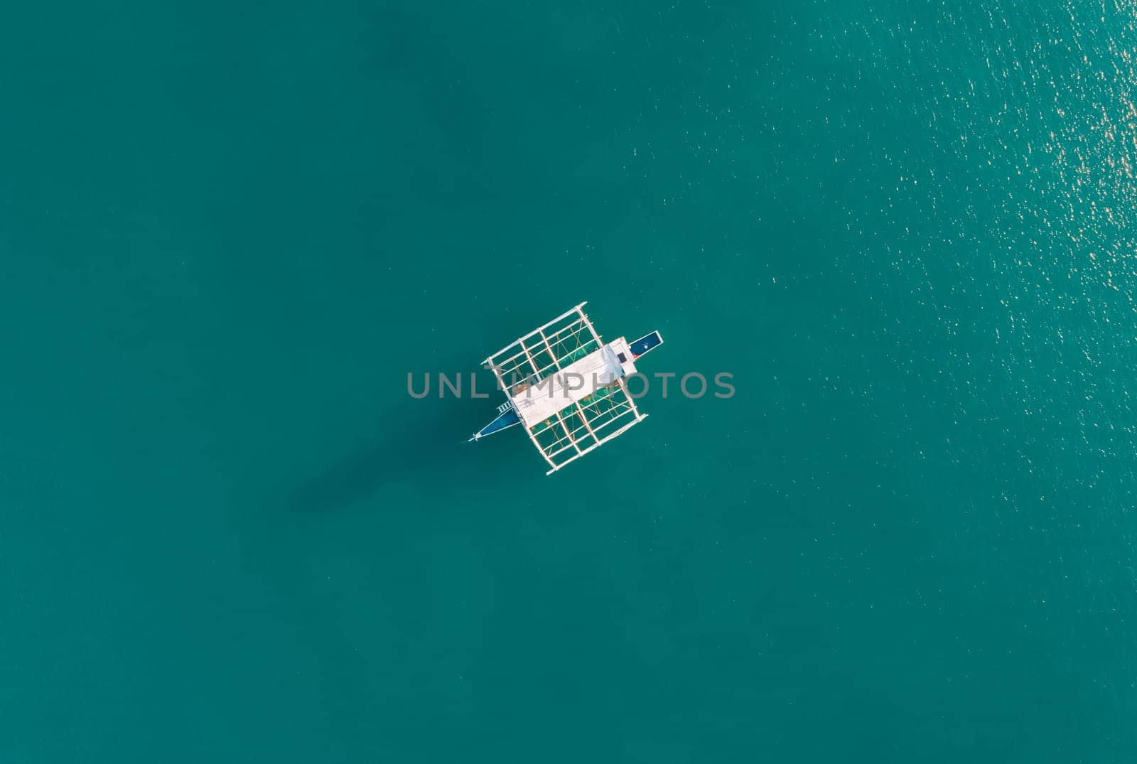 Aerial drone view of boat anchored in the bay with clear and turquoise water on the sunset. Boat in the tropical lagoon. Tropical landscape. El Nido, Palawan island, Philippines. by Busker