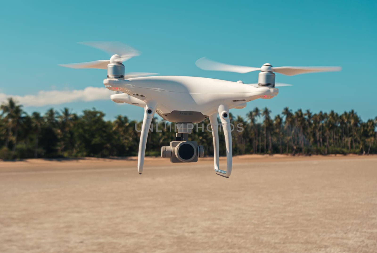 White drone quadrocopter flying against the background of a tropical trees, close-up shot